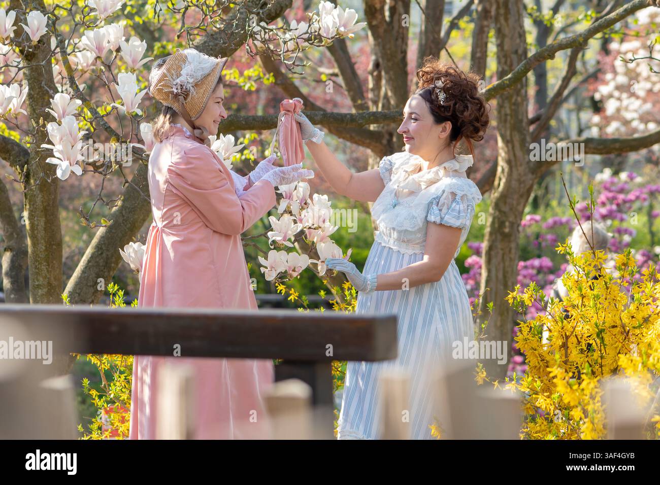 Klassische Atmosphäre der Vergangenheit mit den lebhaften Emotionen zweier Frauen vor dem Hintergrund blühender Natur Stockfoto