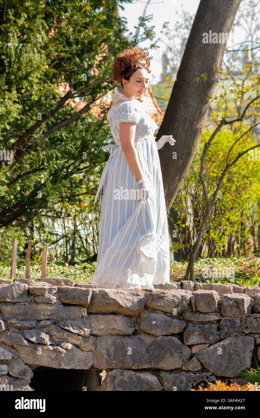 Malerisches Bild einer 35-40-jährigen Frau im Stil der frühen 1800er Jahre mit einem blühenden Garten im Hintergrund Stockfoto
