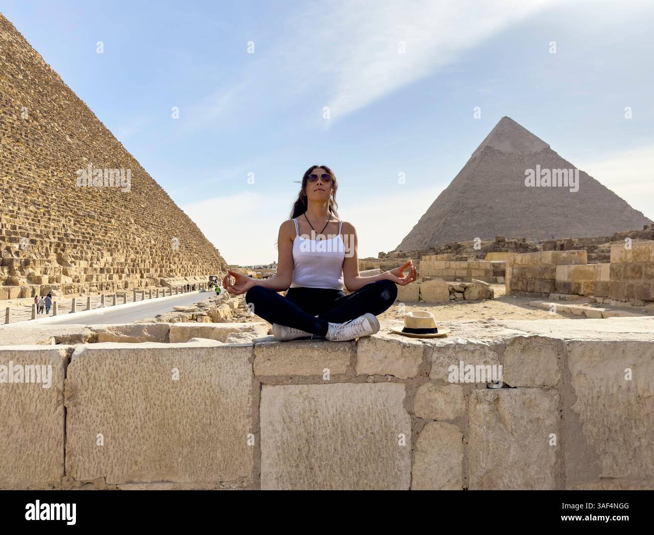 Finden Sie Gizeh Yoga Gelassenheit, während eine Frau mit Mycerinus, Kefren, Keops Pyramiden, Ägypten verbindet. Erleben Sie die Ruhe und antike Energie dieser Ikoni Stockfoto