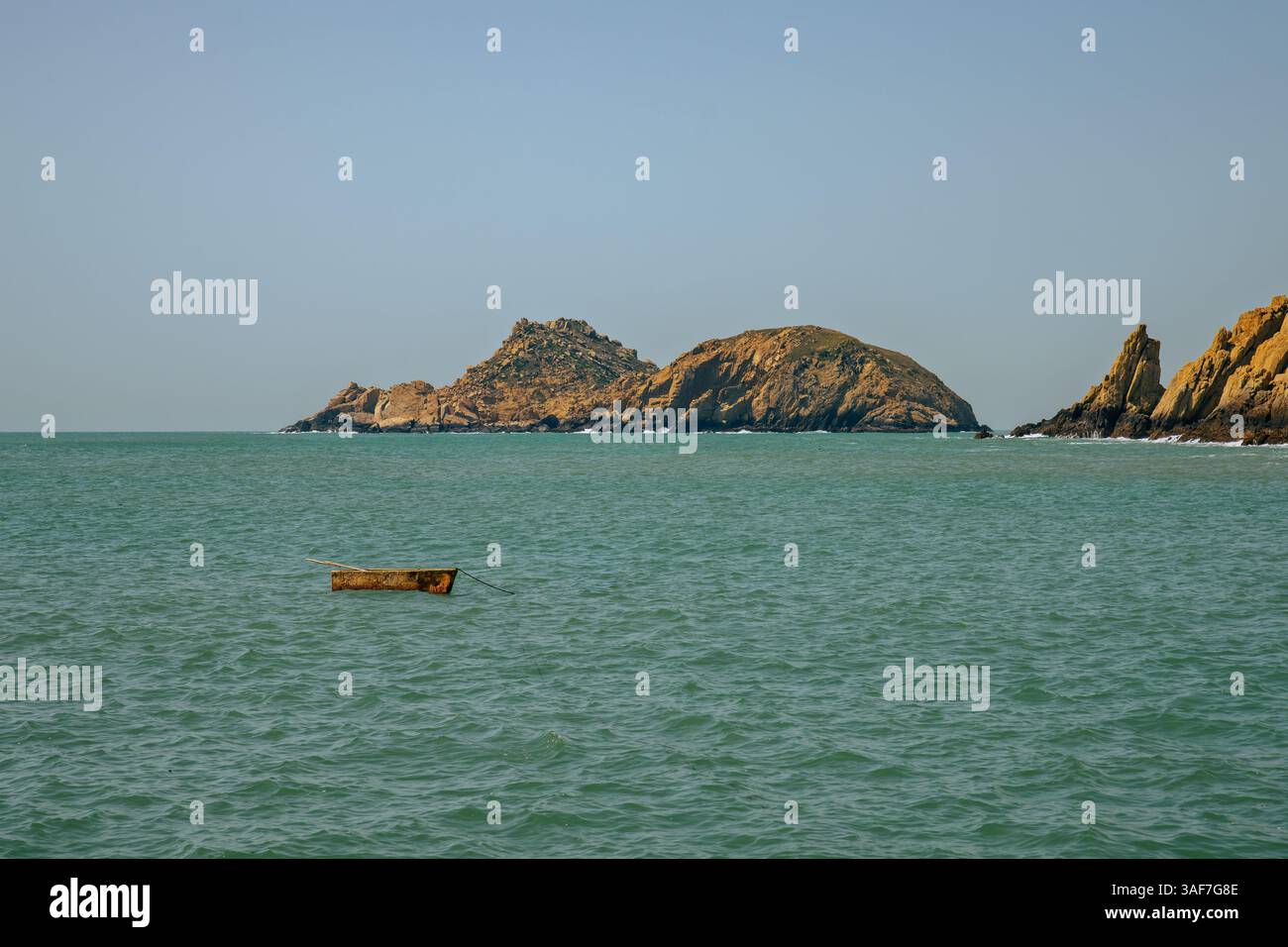 Einsames Boot auf dem Meer mit Klippen im Hintergrund Stockfoto