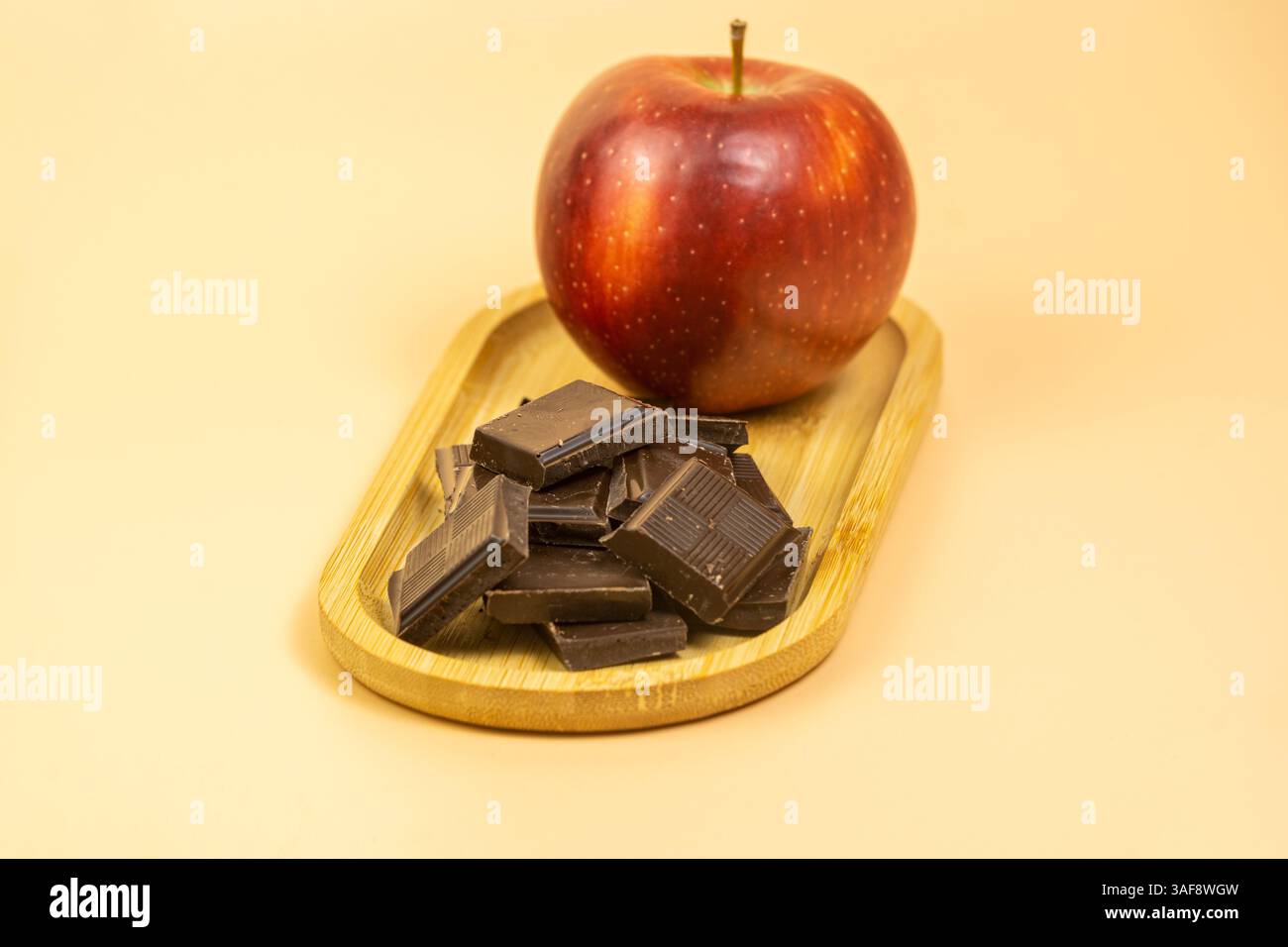 Eine vergrößerte Aufnahme eines kleinen Bambustabletts mit Schokoladenstückchen und einem Apfel Stockfoto