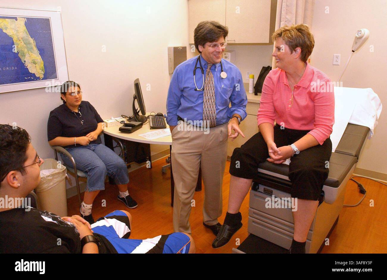 5) Patti Traina (cq / rechts) lacht mit Dr. Steven Goldstein (cq / Mitte rechts) vor ihrer Untersuchung am Montag (8.11.03) in der Bluttransplantationsklinik im Lee Moffitt Cancer Center der University of South Florida. PattiÕs Kinder, Joseph Traina (cq / 16 Jahre alt / ganz links) und Phoebe Traina (cq / 14 Jahre alt / Mitte links) waren für Unterstützung da. **. Patti Traina wurde im Oktober 1997 zum Hillsborough County Firefighter of the Year ernannt. Innerhalb eines Monats wurde bei ihr ein aggressives Lymphom diagnostiziert. Im Juni 1998 wurde sie an einer Knochenmarktransplantation teilgenommen. Es dauerte drei Jahre Stockfoto