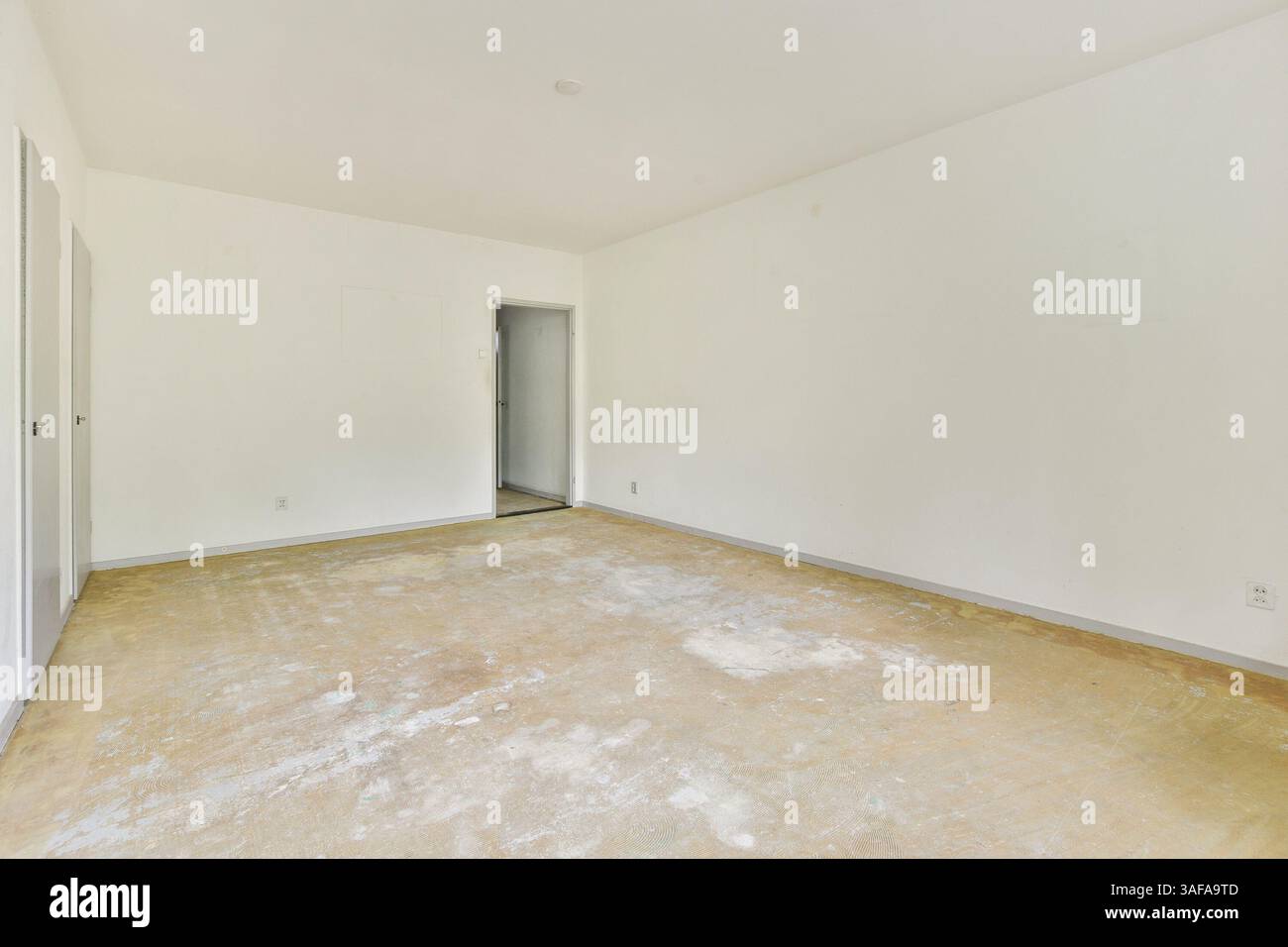 Ein geräumiger, leerer Raum mit hellen Wänden und Sandboden, ideal für Innenarchitektur oder Renovierungsanregungen. Stockfoto