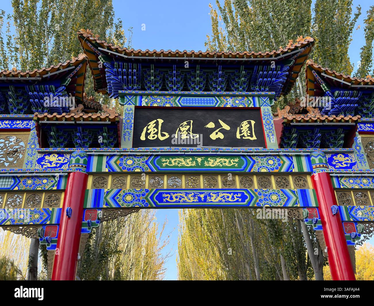 Ein atemberaubender chinesischer Bogengang begrüßt Besucher des Phoenix Park mit herbstlichen Bäumen in Yinchuan, China - Smartphone-aufgenommenes Stockfoto