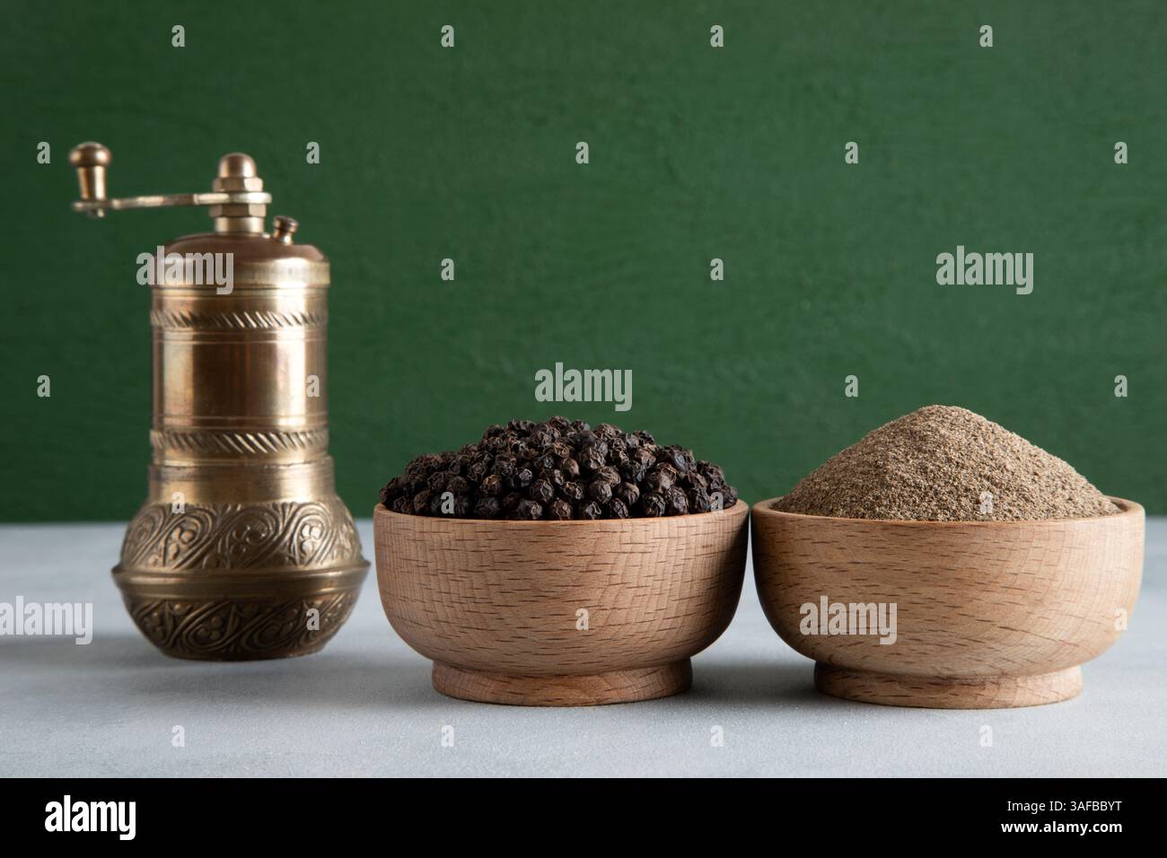 Schwarze Pfefferkörner, gemahlener schwarzer Pfeffer und Metallmahlmaschine Stockfoto
