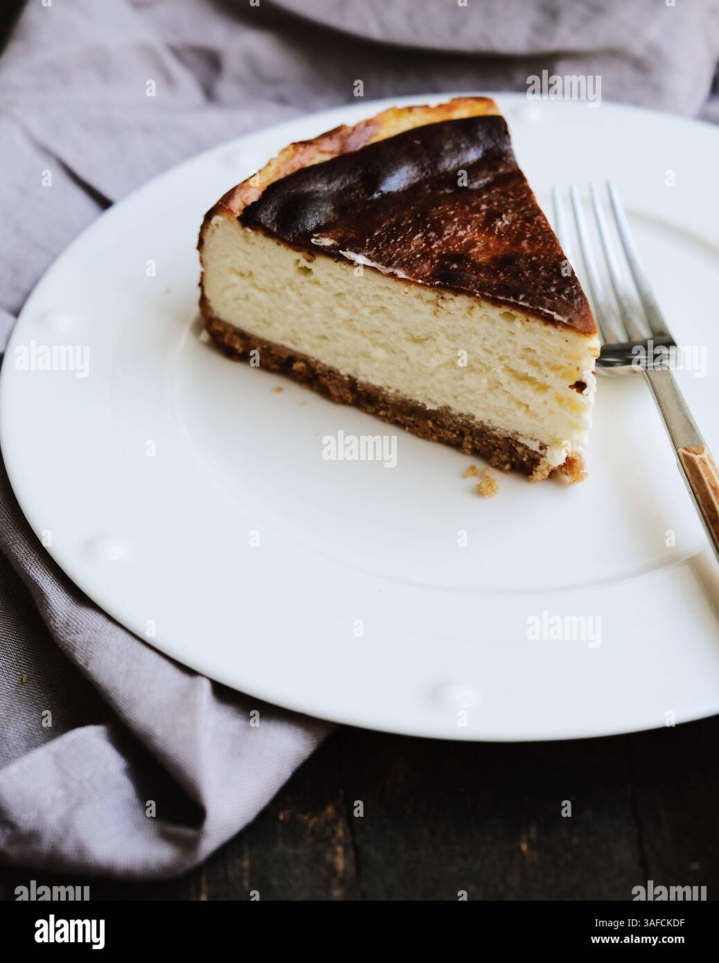Ein Stück gebackener Käsekuchen im New Yorker Stil auf einem weißen Teller Stockfoto