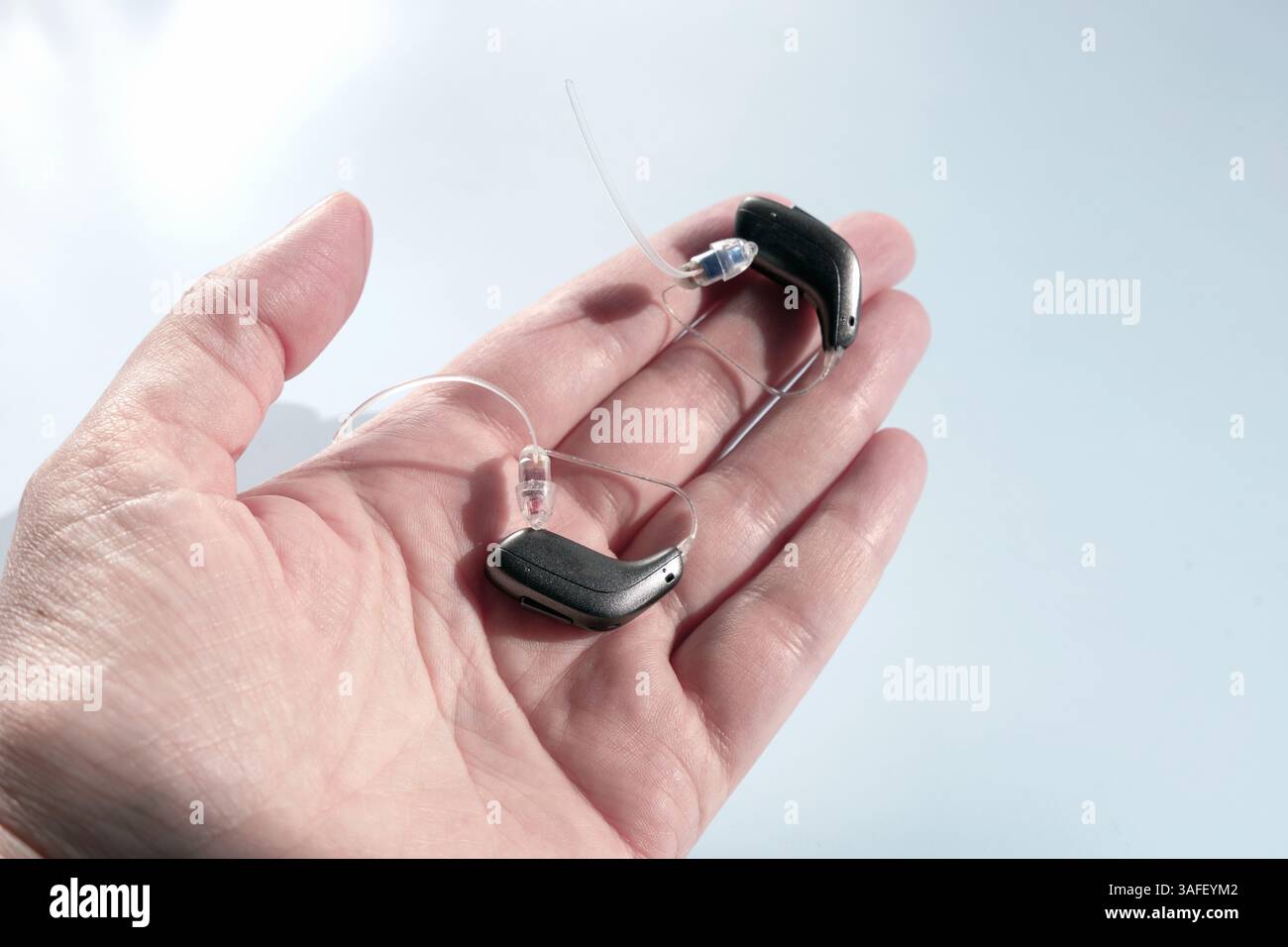 Nahaufnahme einer weiblichen Hand, die ein modernes Hörgerät hält Stockfoto