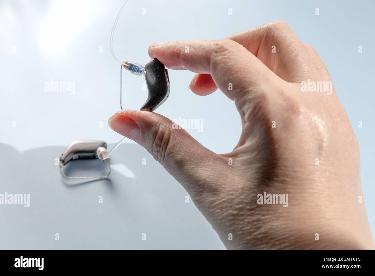 Nahaufnahme einer weiblichen Hand, die ein modernes Hörgerät hält Stockfoto