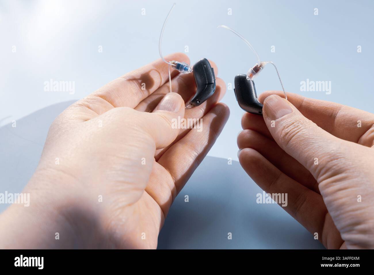 Nahaufnahme einer weiblichen Hand, die ein modernes Hörgerät hält Stockfoto