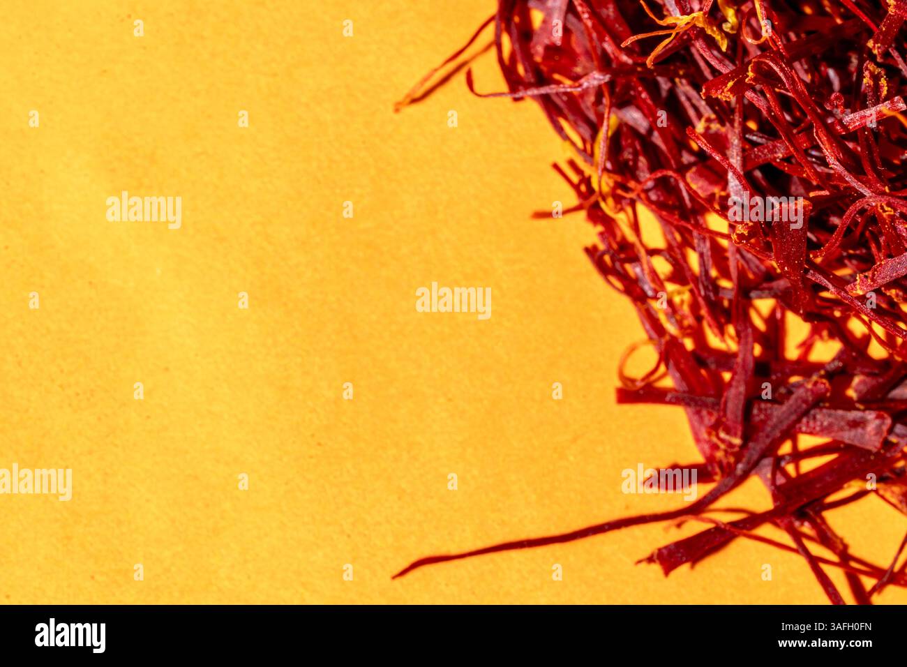 Leuchtend rote Safranfäden am rechten Rand isoliert auf gelb strukturiertem Hintergrund, helles Sonnenlicht, Kopierraum von oben nach unten Stockfoto