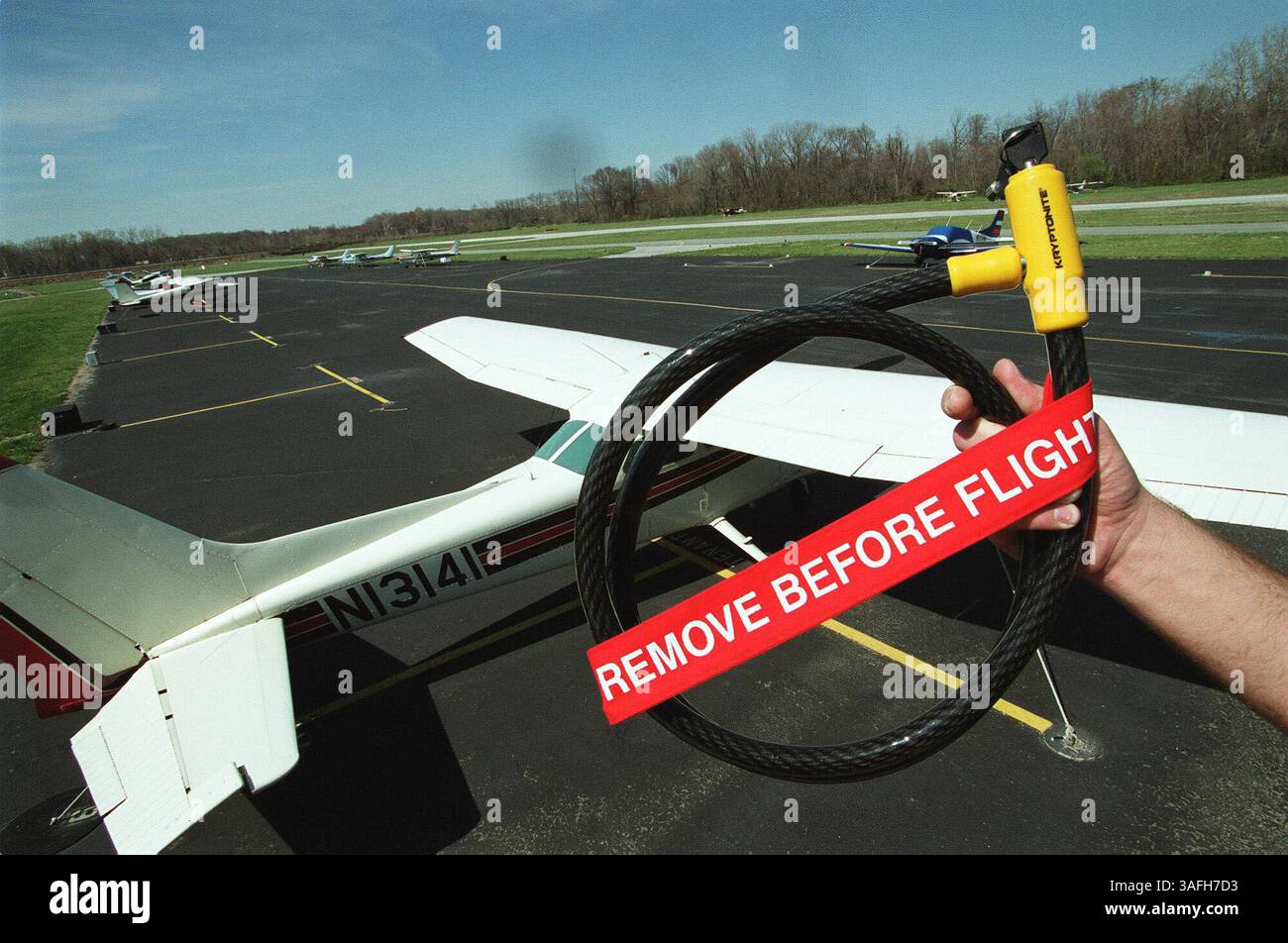 Ein Mitarbeiter des College Park Airport hält am 2. April 2002 ein Propellerschloss in der Hand, das nach dem 11. September von der Maryland National Capitol Parks and Planing Comission an jeden Flugzeugbesitzer am Flughafen geliefert wurde. Die Mieter des Flughafens müssen die Schleuse für ihre Flugzeuge benutzen. Bisher dürfen nur Mieter den Flughafen mit ihren Flugzeugen seit dem 11. September 2001 nutzen. (Bild: Washington Times/ZUMAPRESS.com) Stockfoto