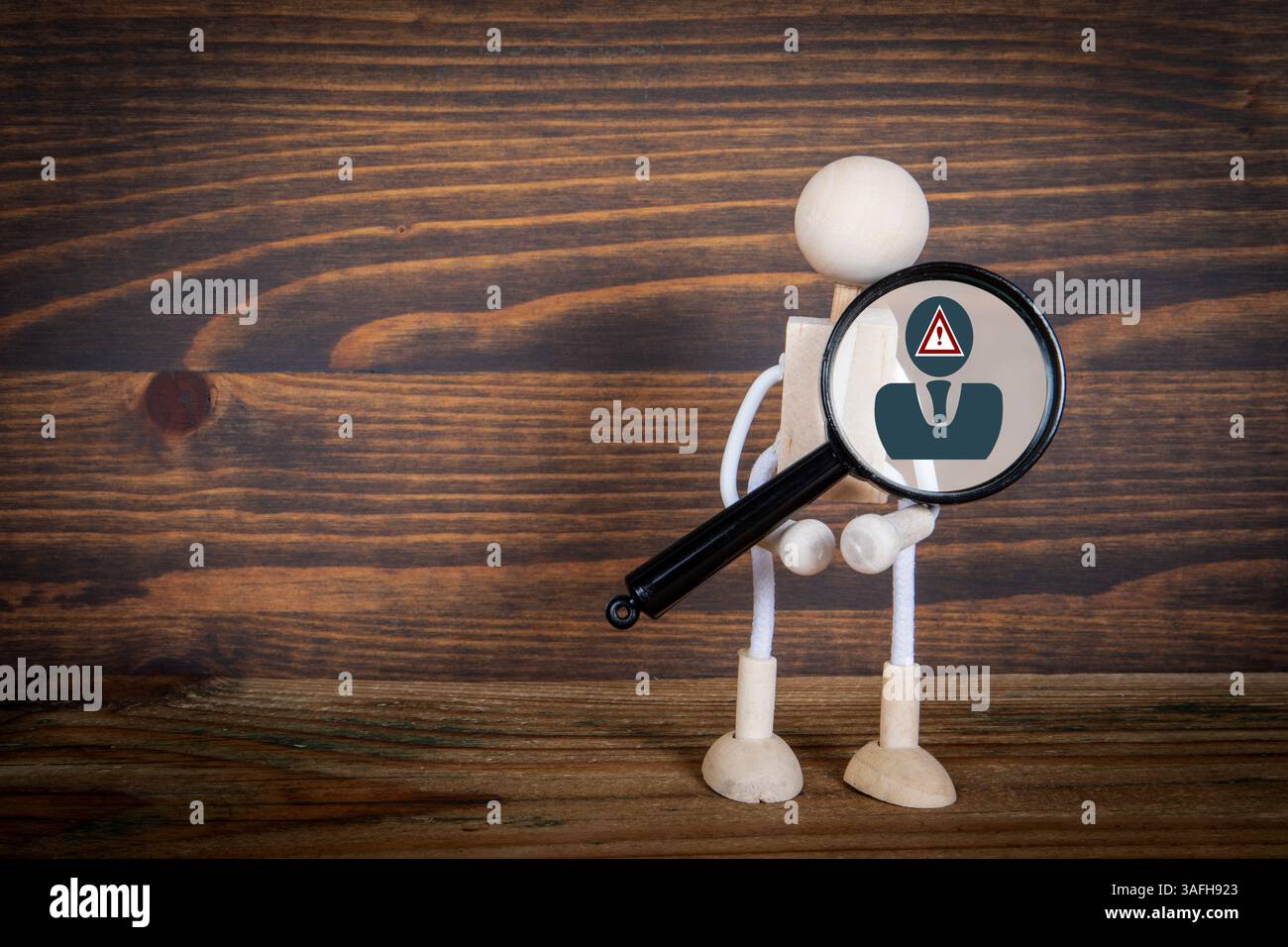 Lupe mit Warnsymbol und Holzfigur für Untersuchung und Vorsicht. Stockfoto