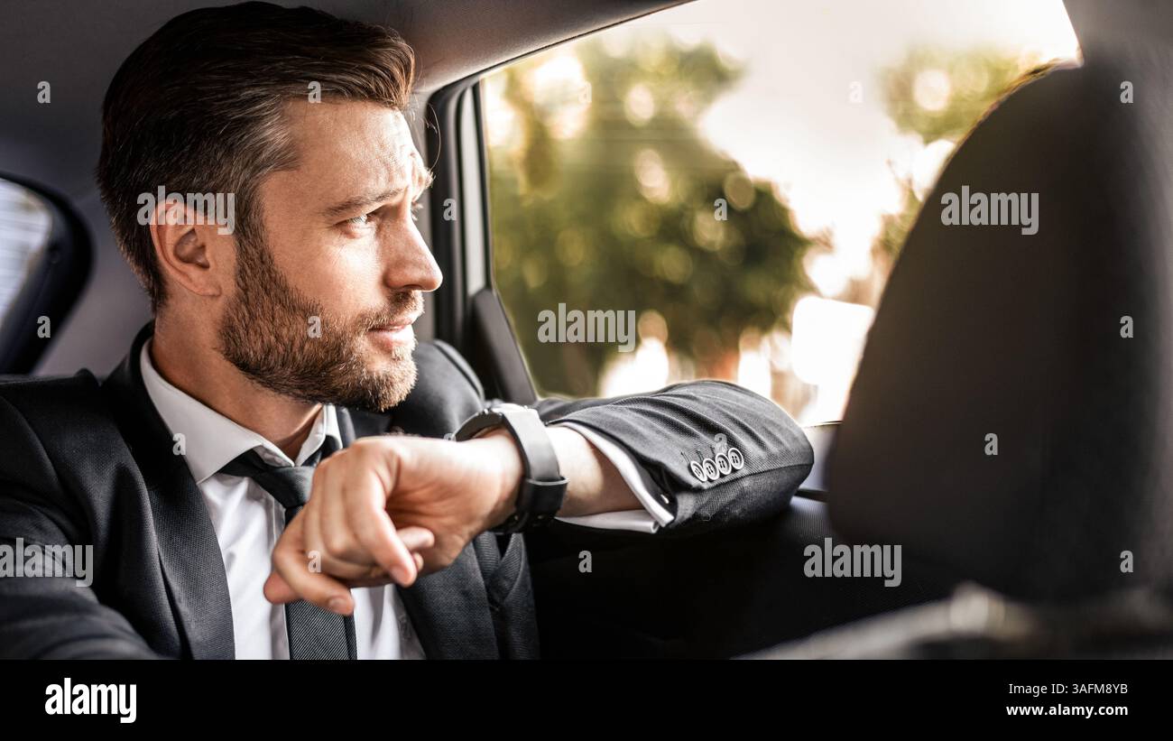 Hübscher bärtiger Mann im Anzug, der im Auto sitzt Stockfoto