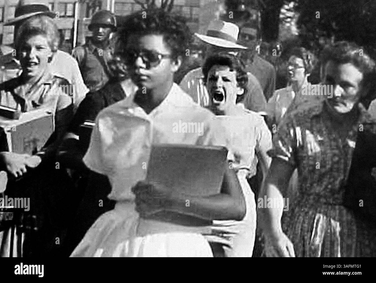 LIEFERUNG AN DEN NP-SCHREIBTISCH - UMLEITUNGEN ---1. Die Studentin Elizabeth Eckford, Front, betritt am 23. September 1957 die Little Rock High School in Little Rock, Arkansas, mit Hilfe von Polizisten der Nationalgarde, die an einer jubelnden Menschenmenge vorbeikommen. Orval Faubus, der Gouverneur von Arkansas, ignorierte Bundesgerichtsanordnungen und verweigerte Afroamerikanern den Zugang zu ganz weißen Schulen. In der sogenannten Little Rock Nine wurden neun schwarze Schüler ausgewählt, um die Central High School zu integrieren. Die Schüler kamen erst in die Schule, als Präsident Dwight D. Eisenhower Bundestruppen nach Arkansas befahl. Das Foto ist Teil einer Sammlung o Stockfoto