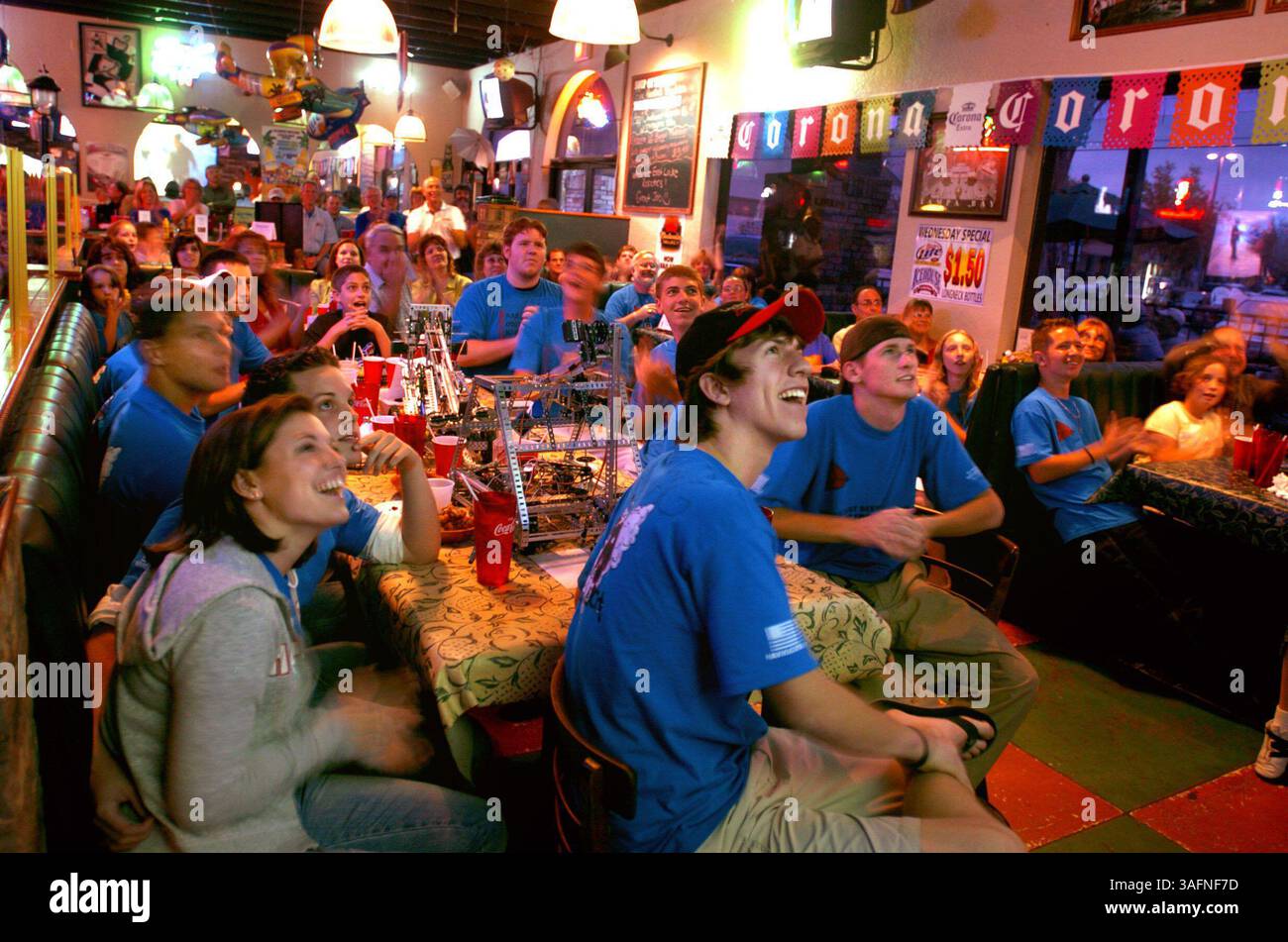 EAST LAKE - (SONNTAG, 1.05.2005) - 1) Mitglieder des Robotik-Clubs der East Lake High School sehen, wie sie am Sonntag (1.05.2005) im Varsity Club in East Lake während der Ausstrahlung von ABC Reality-TV-Show Extreme Makeover: Home Edition auf einer Projektionsleinwand erscheinen. Der Club steuerte Roboterspielzeug für die Show bei, die ein neues Zuhause für das Erschießungsopfer James Dolan und seine Familie baute. Dolan arbeitete in der Spätschicht in einem St. Petersburger Radioshack, als Justin Cudar, 25, hereinkam und am 18. November mit den Dreharbeiten begann. Cudar erschoss Dolan in den Kopf und erschoss die Mitarbeiterin Joana Cruz, 19, und den Kunden Kenneth Powell, 23. Stockfoto