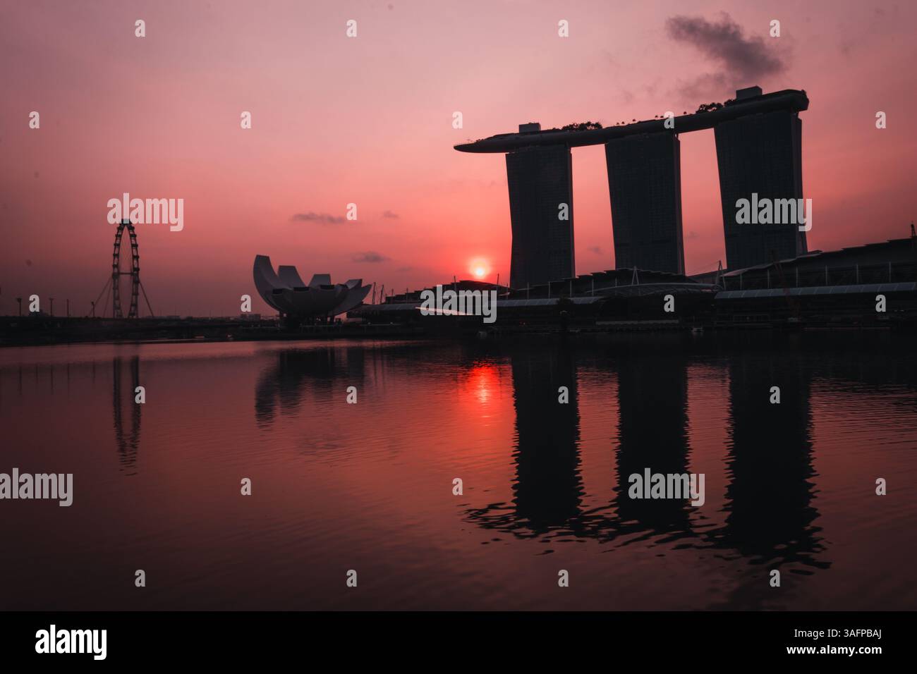 Herrliches Panorama bei Sonnenuntergang von Singapurs Marina Bay Sands und Singapore Flyer, das sich im ruhigen Wasser vor einer pulsierenden Skyline spiegelt Stockfoto