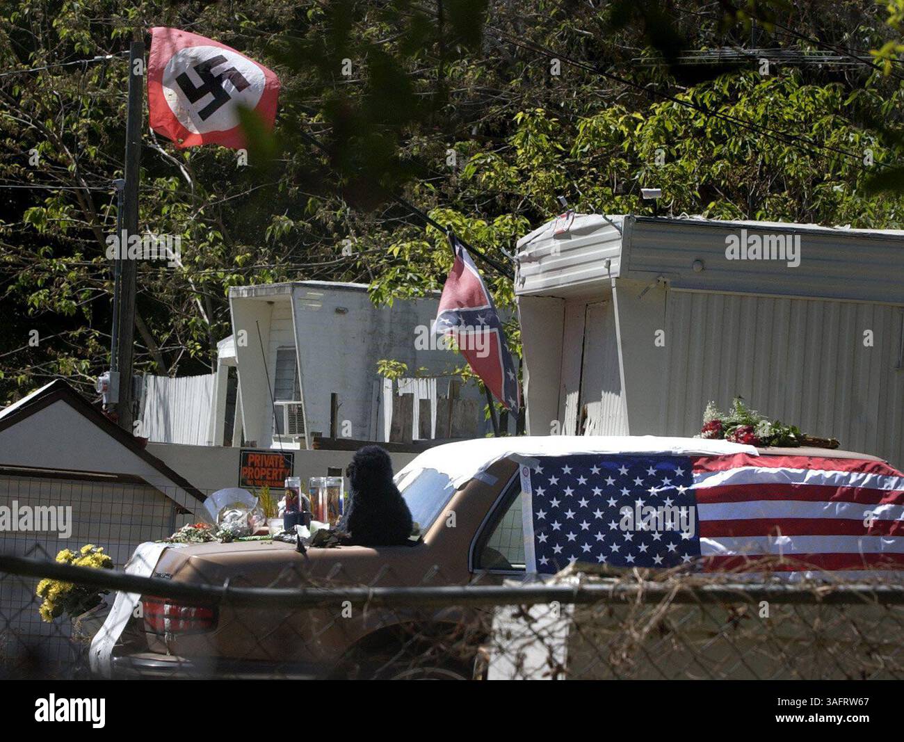 New Port Richey 27.3.2006) Eine Nazi-Flagge fliegt wieder über dem Gelände neben dem Ort, an dem Kris King erstochen wurde und später am Montag in der Teak St. in New Port Richey starb. Kings Freunde schufen ein provisorisches Denkmal, indem sie sein Bonneville mit religiösen Kerzen, Gedichten, Blumen und Notizen in seinem Gedächtnis bedeckten. ZUSAMMENFASSUNG DER GESCHICHTE: Wir besuchen den Anblick, an dem sich eine Gedenkstätte für den Teak Street in New Port Richey gebildet hat, der erstochen wurde und später starb. (Bild: St. Petersburg Times/ZUMAPRESS.com) Stockfoto