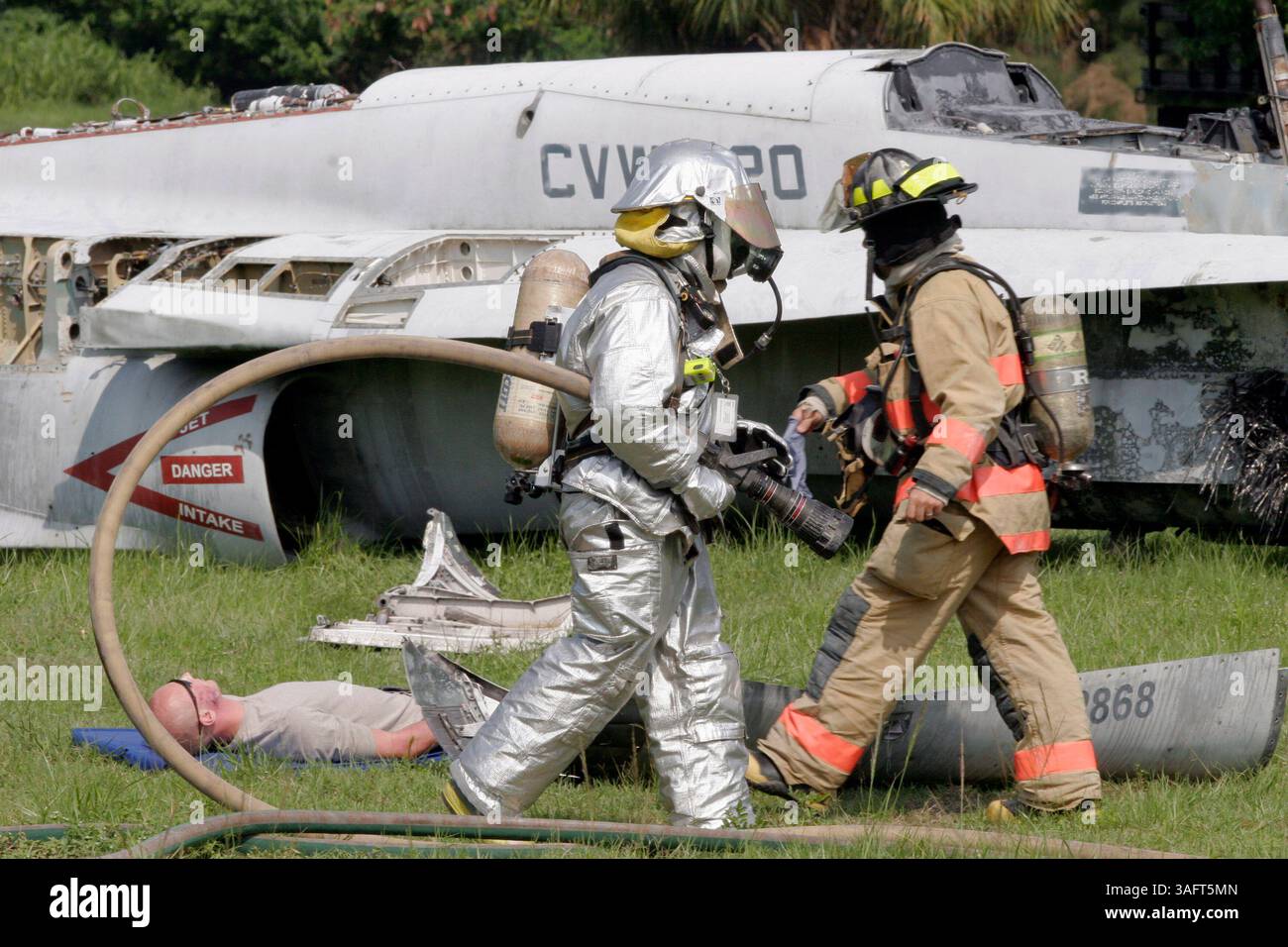 1 von 1.BILDUNTERSCHRIFT: (TAMPA - 19.07.06): (1) Ein 6th Air Mobility Wing Feuerwehrmann (links in Silber) passiert einen Tampa Fire Rescue Feuerwehrmann (rechts) auf seinem Weg, um einem der ''Opfer' des Flugzeugabsturzes während der Übung zur Reaktion auf schwere Unfälle Mittwoch zu helfen (Credit Image: St Petersburg Times/ZUMAPRESS.com) Stockfoto
