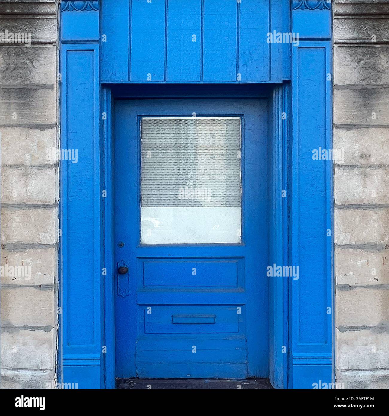 Hellblaue Tür mit einem Milchglasfenster in einer verwitterten Steinfassade in Chicago - Smartphone-aufgenommenes Stockfoto