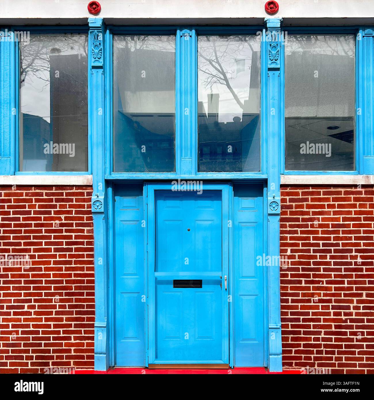 Hellblaue Tür- und Fensterrahmen stehen in einem markanten Chicago-Straßenbild in einem scharfen Kontrast zu roten Ziegelsteinen und weißen Zierleisten - Smartphone-aufgenommenes Stockfoto
