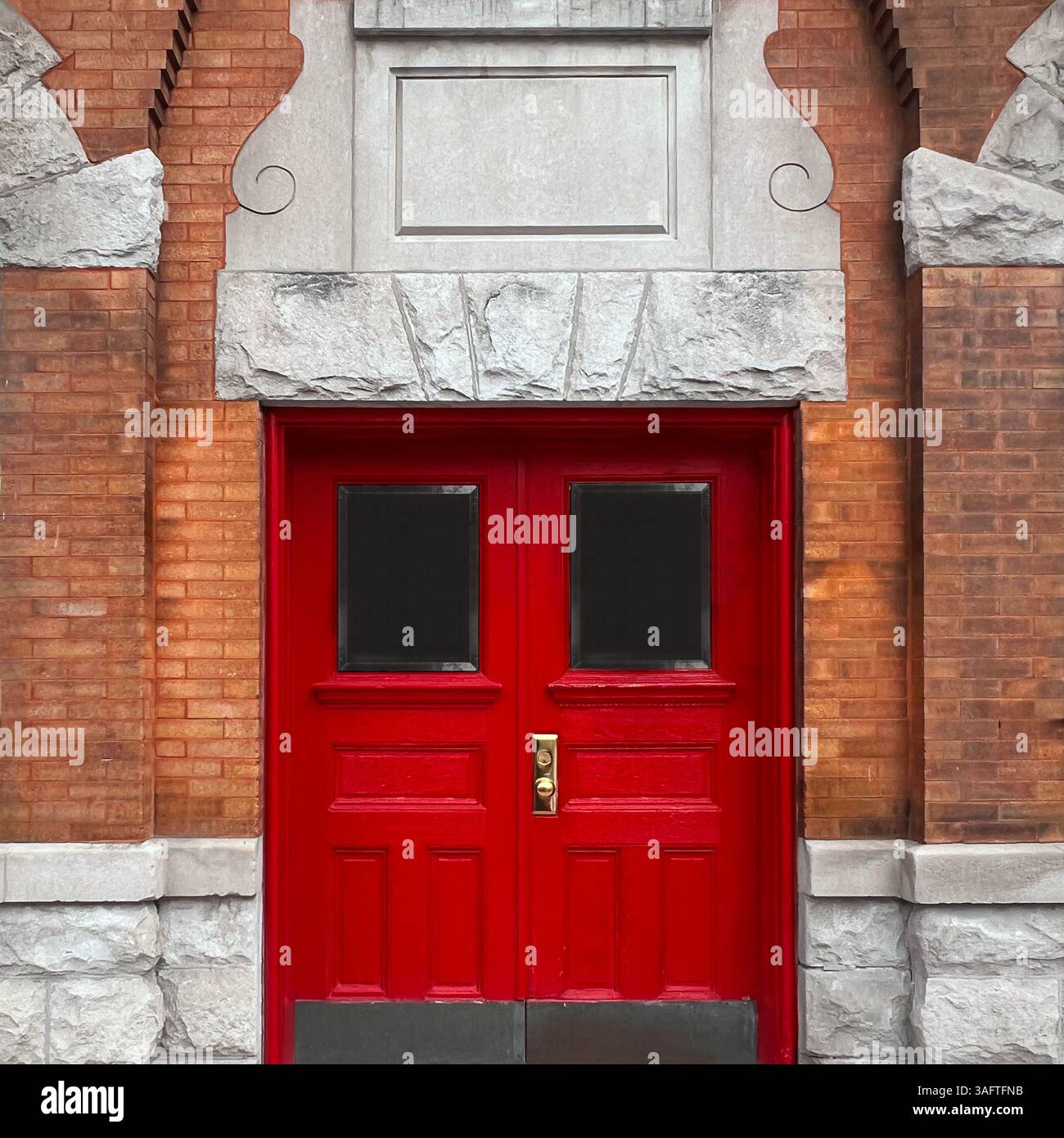Hellrote Doppeltüren mit weißem Steinbogen und Schlussstein in einem historischen Backsteingebäude in Chicago. - Smartphone-aufgenommenes Stockfoto