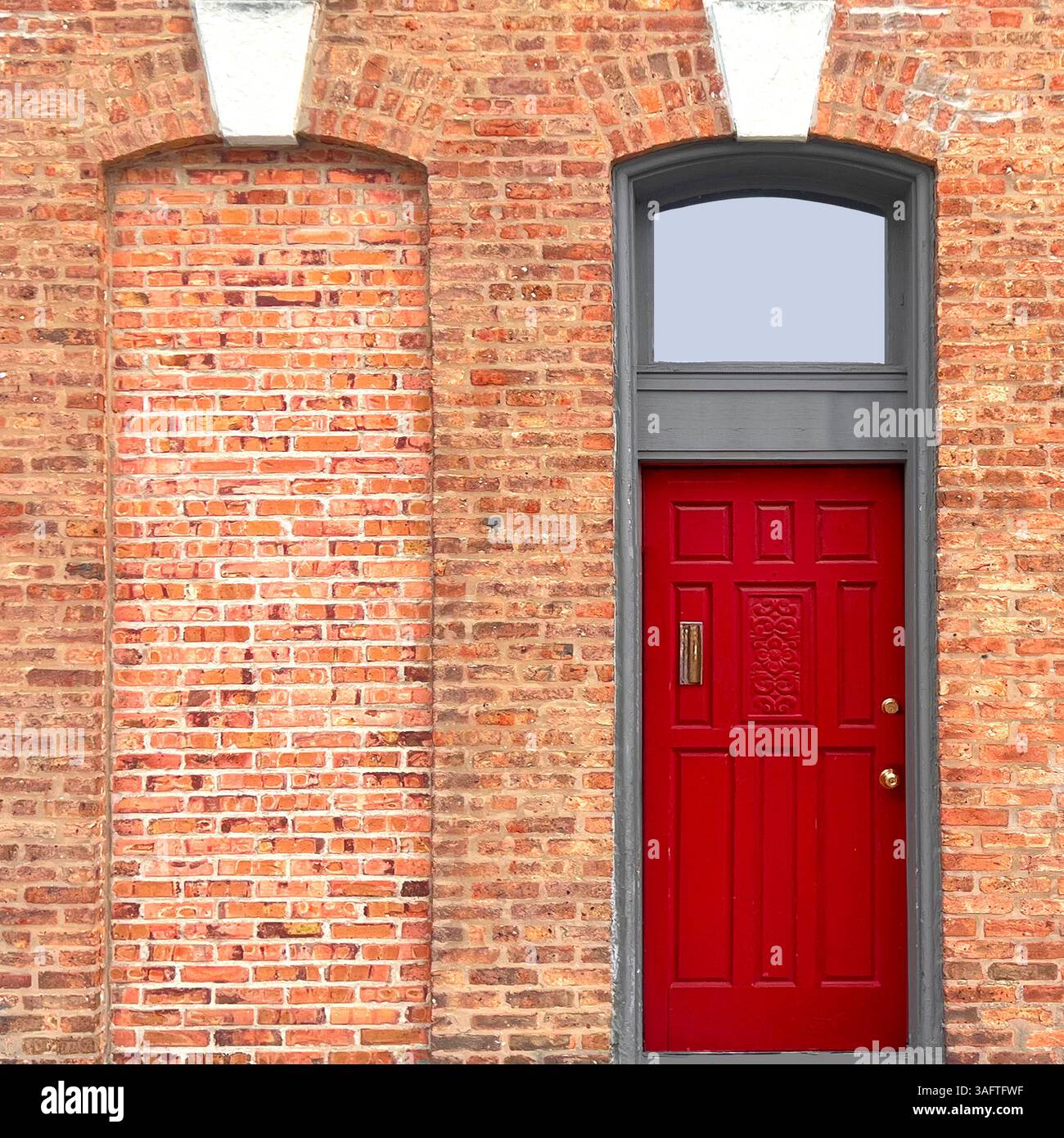 Ein kunstvoller roter Eingang in Chicago mit detaillierten weißen Steinverkleidungen und Bogenfenstern im Fanlight-Stil versprüht historischen Charme und Symmetrie - Smartphone-aufgenommenes Stockfoto