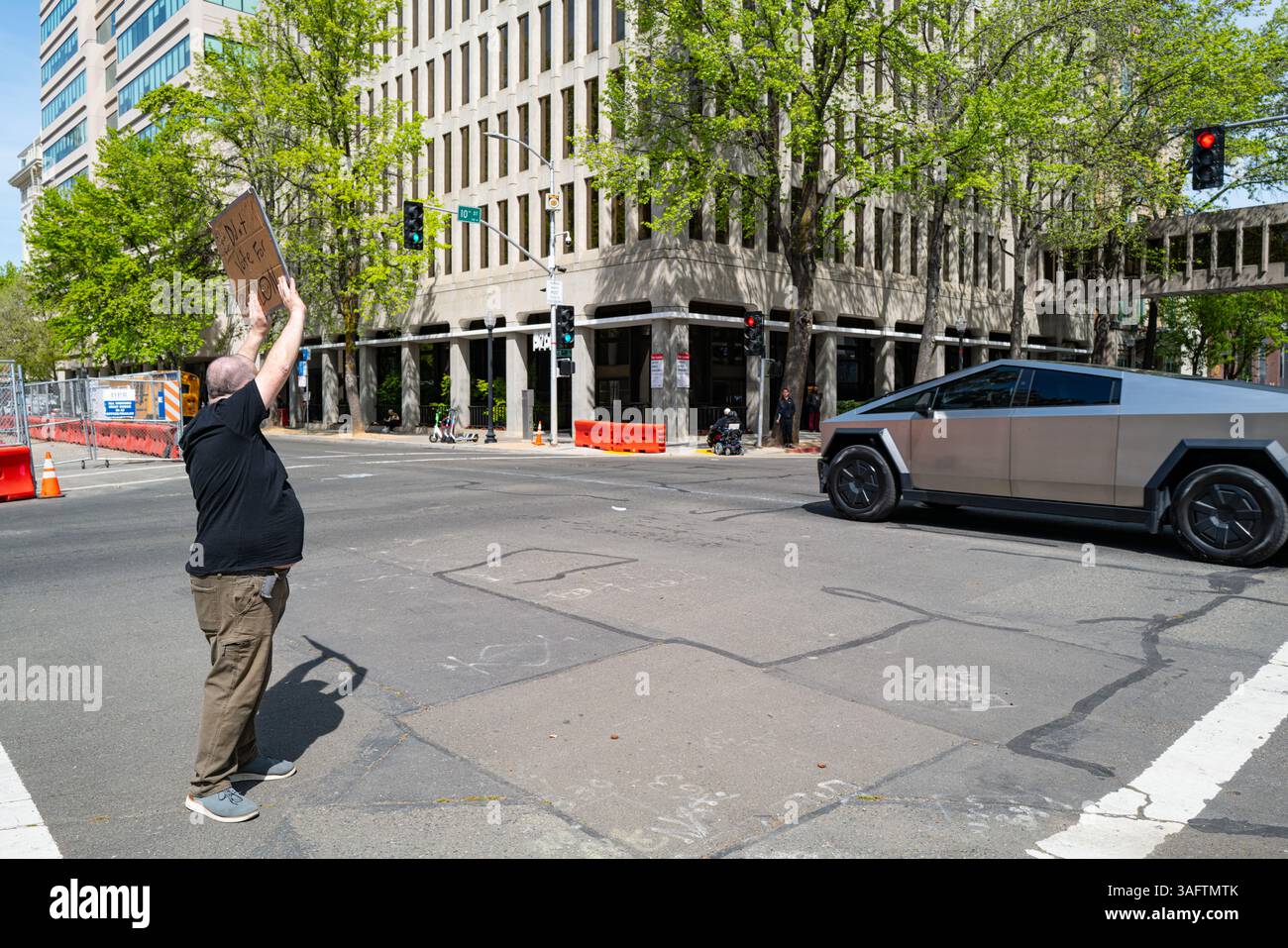Ein Aktivist hält ein Schild in der L Street hoch, dass er Elon Musk nicht zu einem vorbeifahrenden Cybertruck bei der Demonstration der Hands-off 50501 wählte. Stockfoto
