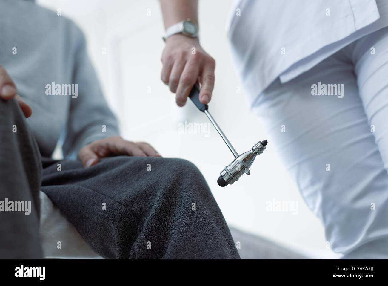 Ärztliche Untersuchung des Kniereflexes des Patienten mit neurologischem Hammer bei körperlicher Untersuchung in der Klinik. Stockfoto