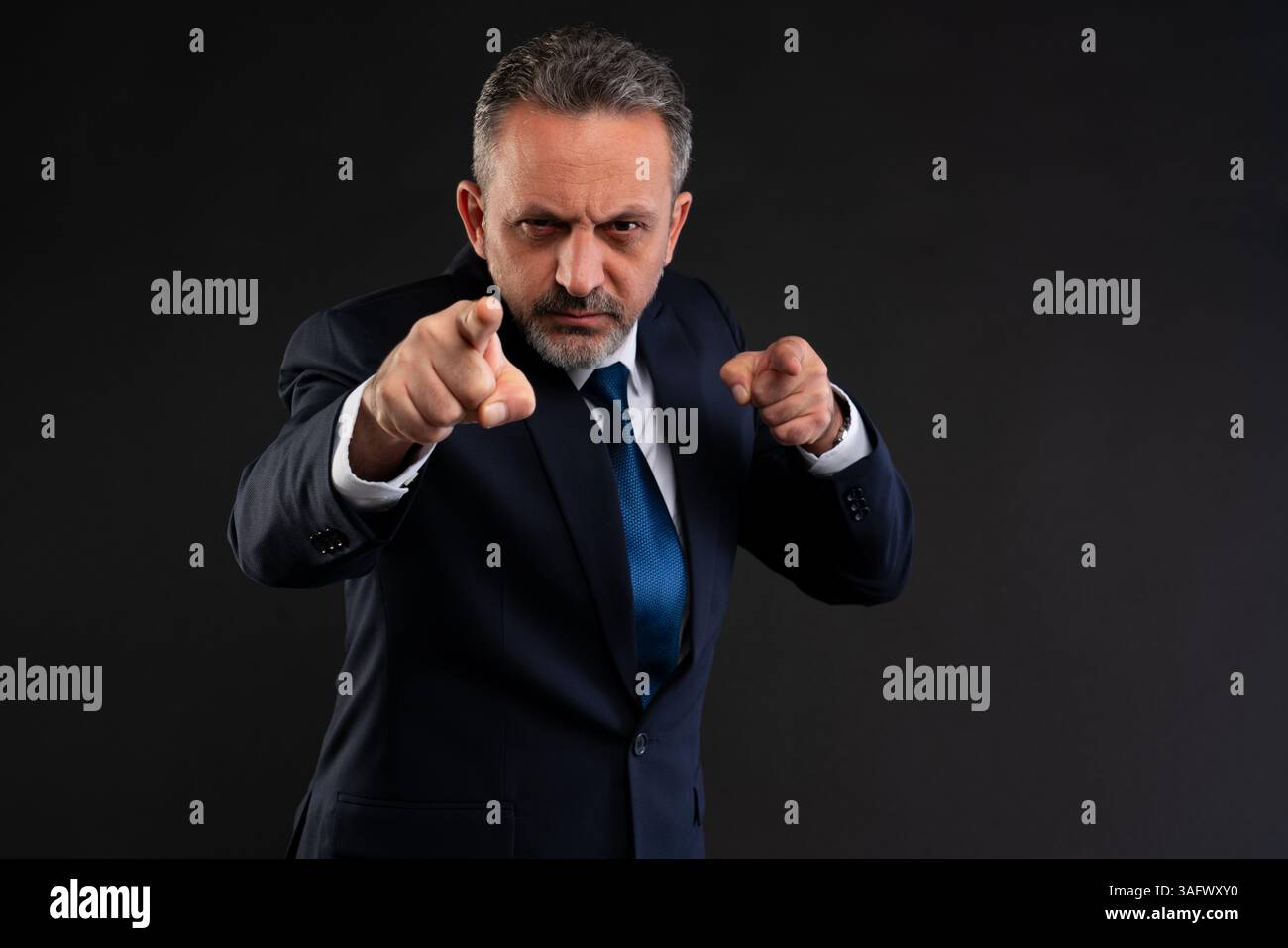 Selbstbewusster, reifer Geschäftsmann in einem Anzug, der direkt mit beiden Händen zeigt und Entschlossenheit, Autorität oder Herausforderung im Unternehmenskontext ausdrückt. Stockfoto Selbstbewusster, reifer Geschäftsmann in einem Anzug, der direkt mit beiden Händen zeigt und Entschlossenheit, Autorität oder Herausforderung im Unternehmenskontext ausdrückt. Stockfoto