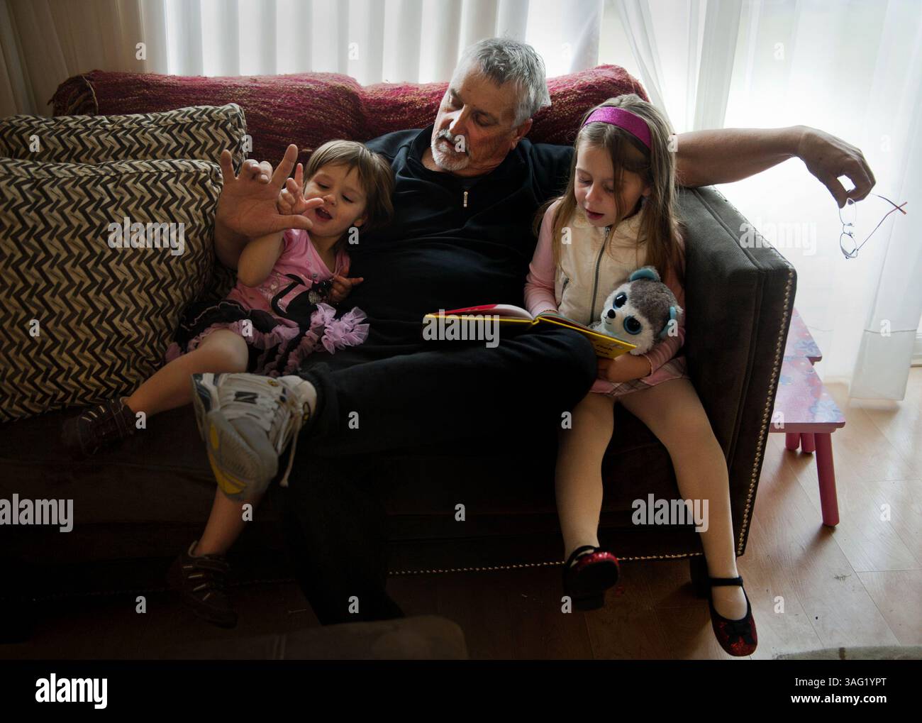 14. März 2012: Napa, Kalifornien, USA: DON HATFIELD interagiert mit seinen Enkeln ARIEL, 2, links, und EVA, 4, richtig, als sie "ein Fisch, zwei Fische, Roter Fisch, Blauer Fisch" in einem Haus lesen, zogen sie gerade in den Tag zuvor. Er kümmert sich um seine Enkelkinder und trauert immer noch um seine Tochter Rachel, die vor zwei Wochen brutal erstochen wurde. Er hat das Sorgerecht für die Kinder beantragt, seit ihr Vater Todd wegen des Mordes verhaftet wurde, aber sich für nicht schuldig bekennt. (Bild: © Renee C. Byer/Sacramento Bee/ZUMAPRESS.com) Stockfoto