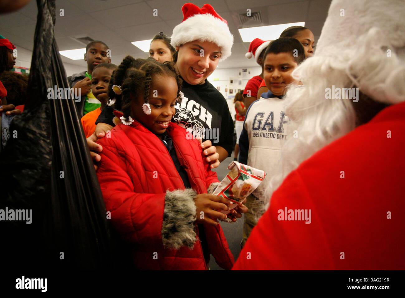 Tampa 20.12.2007) die Schülerin der Sligh-Grundschule Ivelisse Santos, 12, steht hinter Shavaria Funches, 7, während sie mit dem weihnachtsmann spricht, nachdem sie ein Geschenk von Schülern der Sligh Middle School erhalten hat, die am 20. Dezember 2007 ein Spielzeug-Give-Away für Schüler der James Elementary organisiert haben. Die Sligh-Schüler sangen und tanzten mit den Kindern, bevor sie ihre Geschenke erhielten. „Es war aufregend, alle Zweitklässler glücklich und aufgeregt zu sehen“, sagte Ivelisse. (Bild: St. Petersburg Times/ZUMAPRESS.com) Stockfoto
