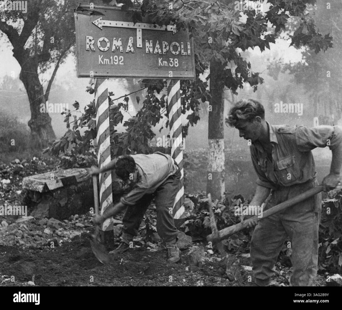 Sappers reparieren die Straße nach Rom -- zwei königliche Ingenieure der 5. Armee reparieren eine Straße unter einem Schild, das den Weg nach Rom zeigt. Januar 1943. (Foto von britischem Offiziellen Foto). Stockfoto