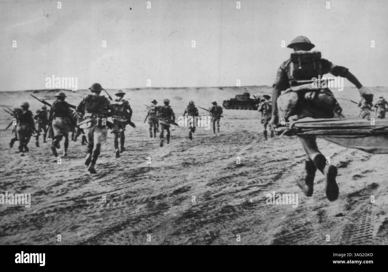 Sturming A Ridge im Wüstenkrieg - die britische Infanterie steigt im libyschen Wüstenkrieg auf den Doppel-Rücken in Richtung Ridge vor, in dem Rommels Männer gerutscht wurden. Panzer im Hintergrund ist ein Achsenfahrzeug, das bei ihrem Gegenangriff, der diesem britischen Angriff vorausging, deaktiviert wurde. November 1942. (Foto von AP Wirephoto). Stockfoto