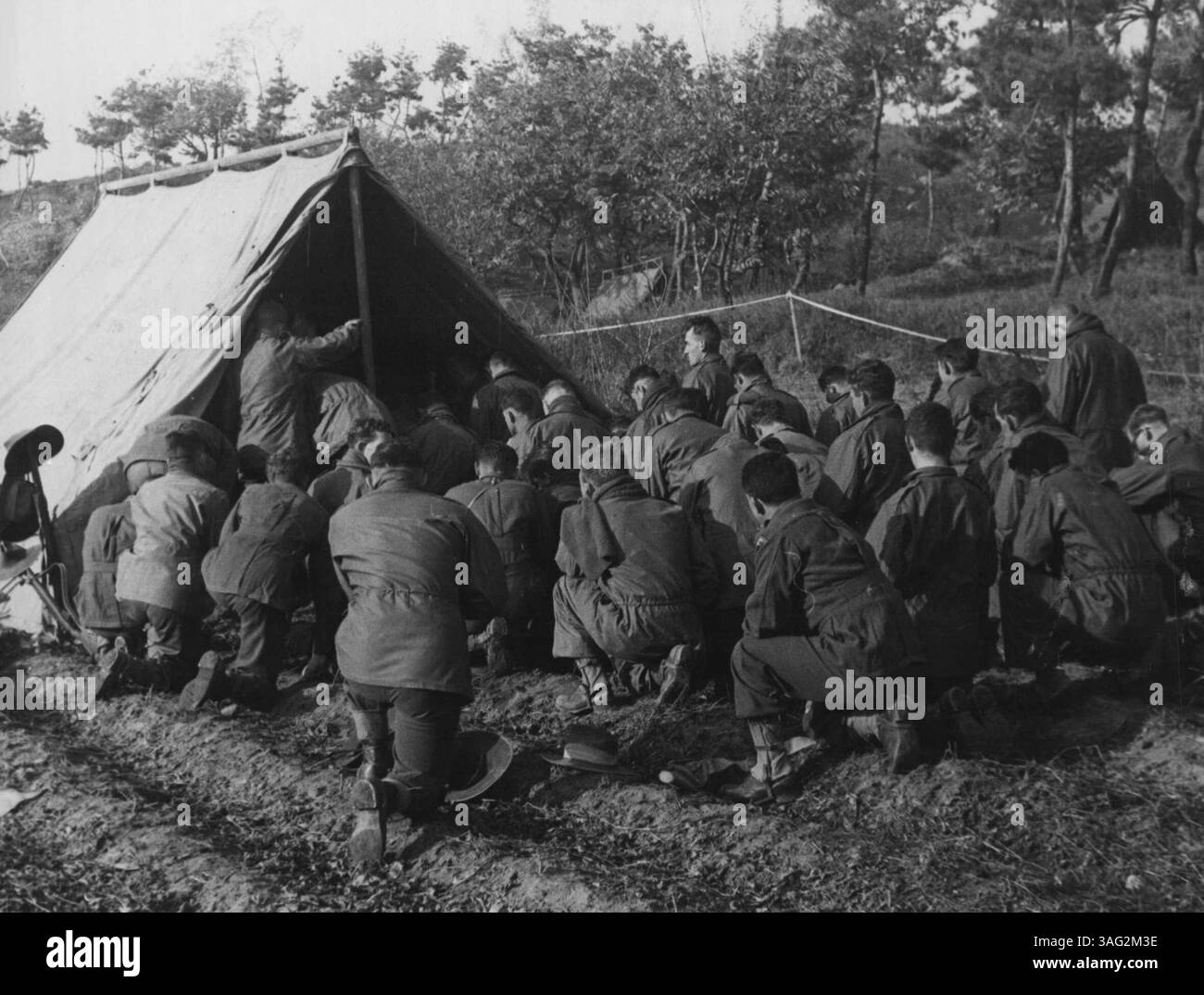 Abteilung für Öffentlichkeitsarbeit, Hauptquartier, BCOF, Japan - Männer des 3. Bataillons Royal Australian Regiment nehmen am 1. November an der Messe im BN HQ in der Nähe von Chongju, Korea Teil. Der Celebrant, Chaplin E. B. Phillips, ist im Zelt verdeckt. Juli 1950. Stockfoto