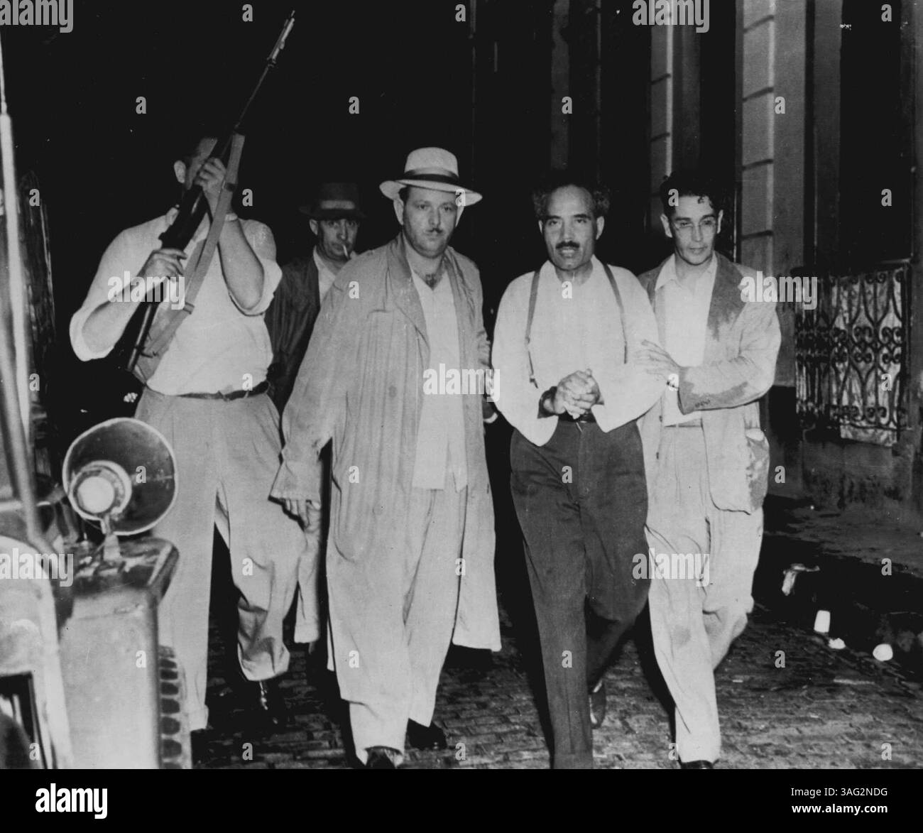 Puerto-ricanischer Nationlist-Führer verhaftet -- stellvertretender Polizeichef Pedro Albizu Campos (zweiter von rechts) von seinem Haus in San Juan, Puerto Rico, heute nachdem der Puerto-ricanische Nationalist-Parteiführer unter Arrest gestellt wurde. Er wurde in eine inselweite Zusammenführung eingesperrt, die durch den Puerto-ricanischen Aufstand und den Anschlag auf das Leben von Präsident Truman in Washington ausgelöst wurde. Dieses Foto wurde von Juan E. Ortiz von der Zeitschrift Alma Latina von San Juan gemacht. November 1950. (Foto von AP Wirephoto) Stockfoto