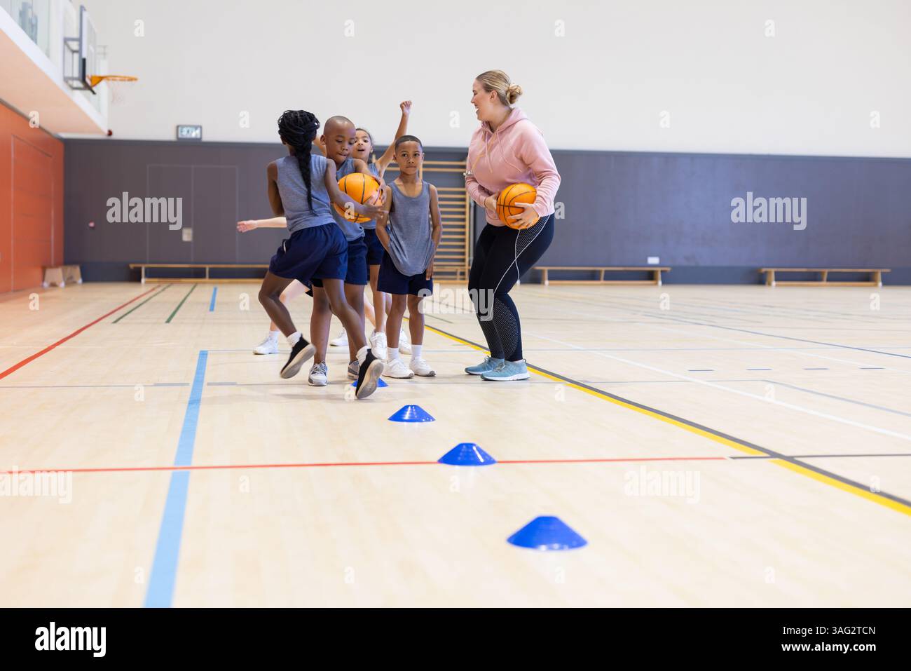 Basketball spielen, verschiedene Kinder in der Schule trainieren mit weiblichen Trainern und Kegeln Stockfoto