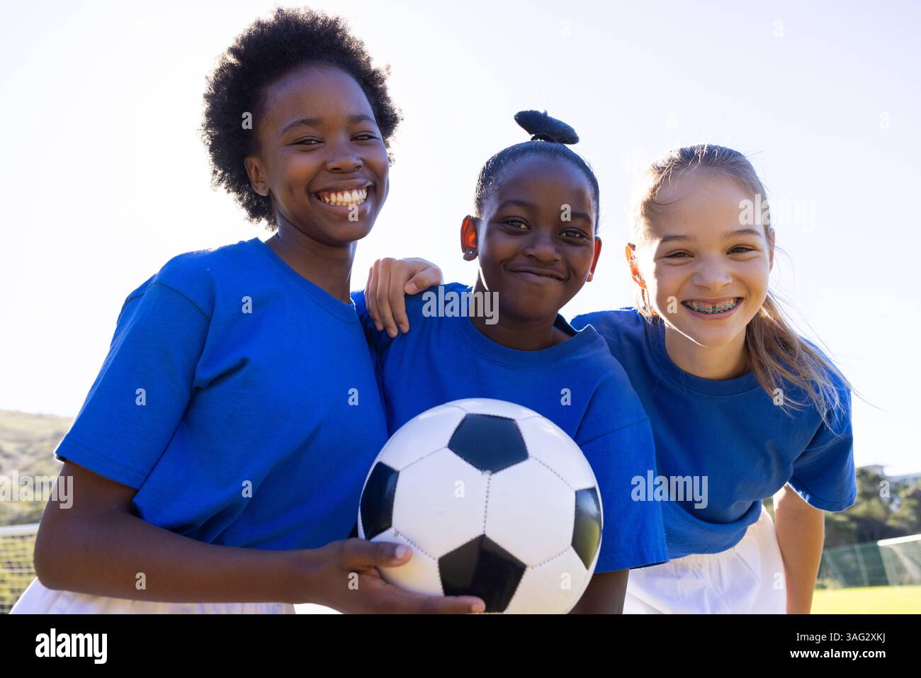 Lächelnde Schule verschiedene Mädchen, die Fußball halten und gemeinsam Outdoor-Aktivitäten genießen Stockfoto
