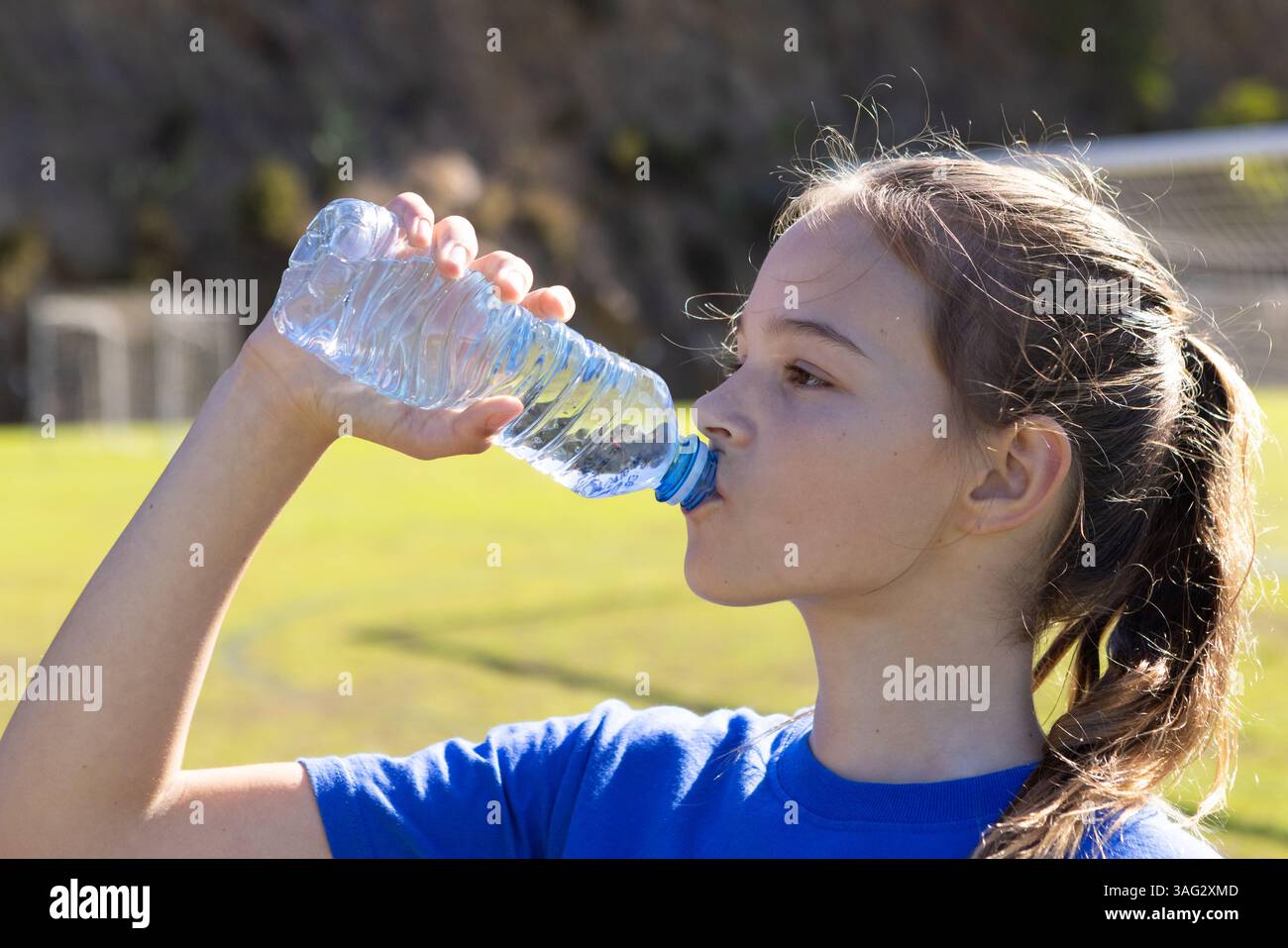 Trinkwasser aus der Flasche, Mädchen bleibt während der Schulaktivität im Freien mit Wasser versorgt Stockfoto