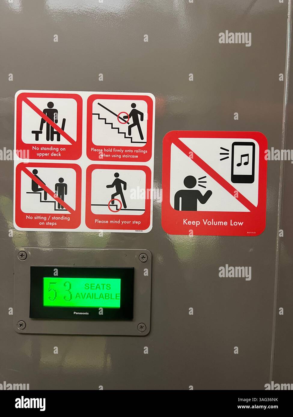 Vertikale Ansicht. Bus-Aufkleber Warngrafiken auf Bus. Ein grünes digitales Bedienfeld, das die Anzahl der verfügbaren Sitze auf dem Oberdeck anzeigt. Singapur. - Smartphone-aufgenommenes Stockfoto