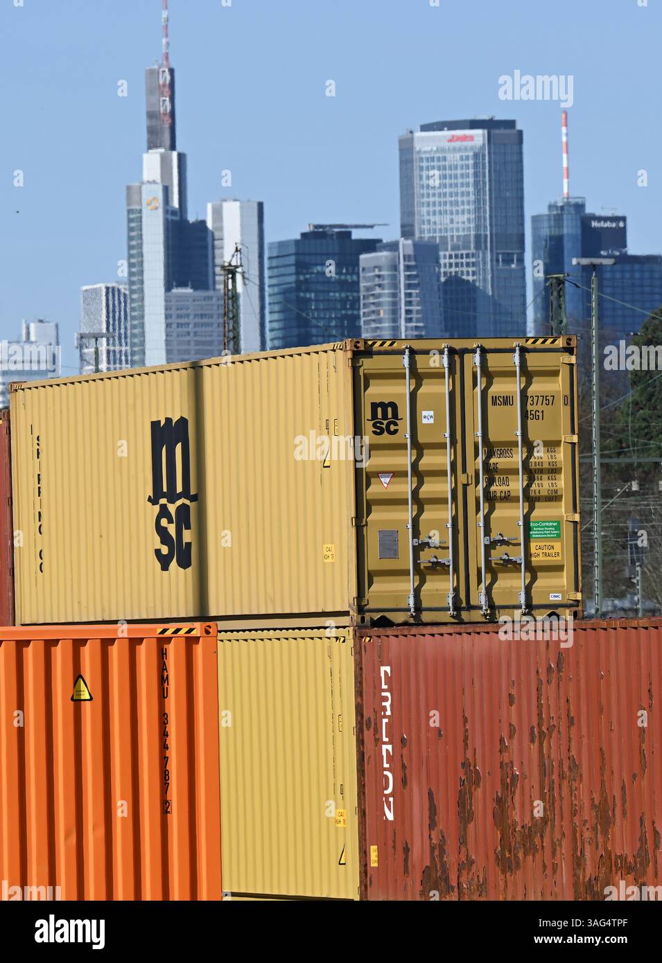 08. April 2025, Hessen, Frankfurt/Main: Im Osten der Bankenstadt werden Gütercontainer auf dem Gelände des Umschlagbahnhofs DB gestapelt. Die Wolkenkratzer der Bank-Skyline erheben sich hinter ihnen. US-Präsident Trumps aggressive US-Zollpolitik kann auch als Handelskrieg gegen den Rest der Welt angesehen werden. Nach drei Tagen des Handels mit dem Rot startete der DAX am Dienstag wieder höher. Foto: Arne Dedert/dpa Stockfoto