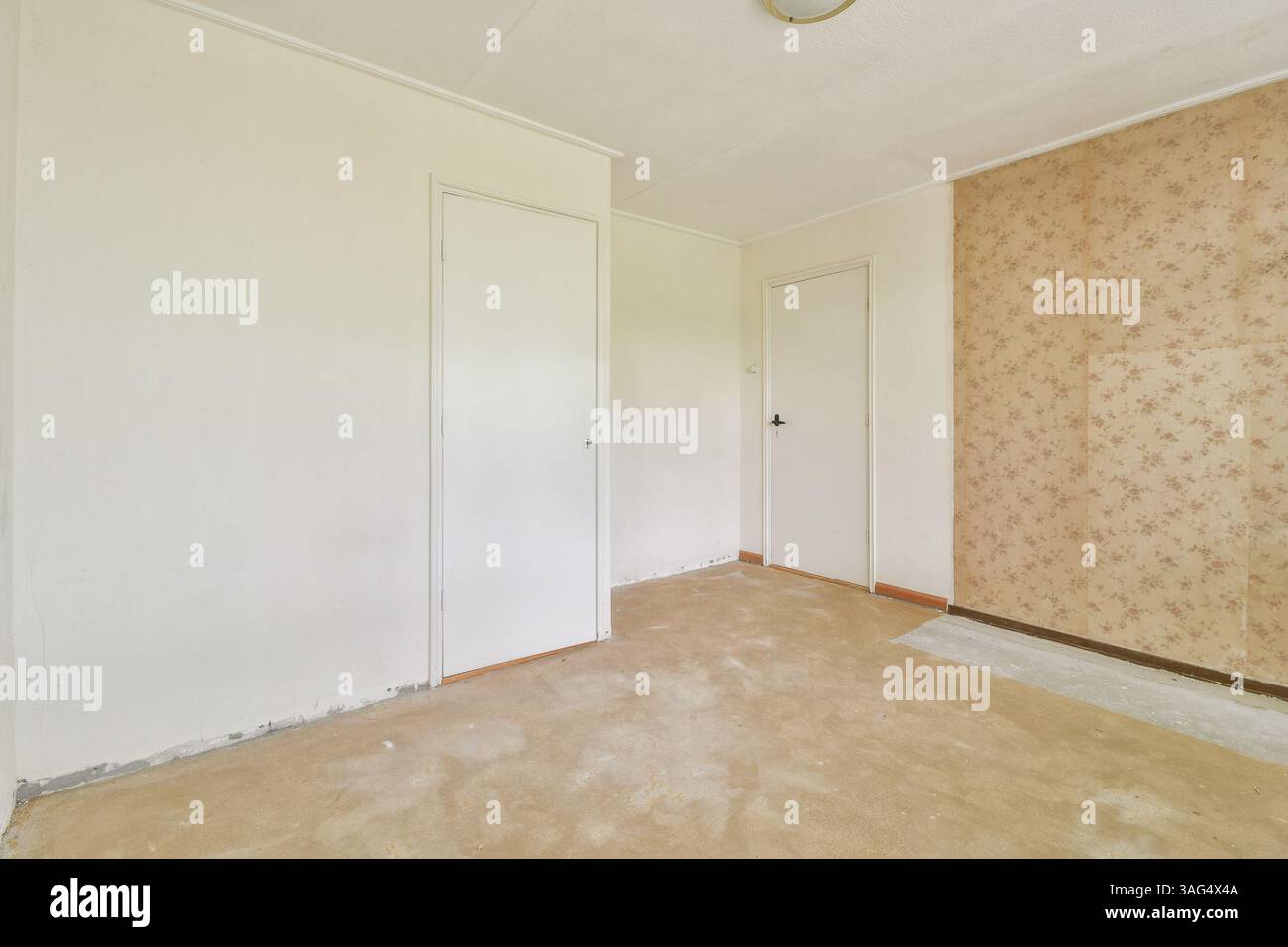 Ein leeres Zimmer mit neutralen Wänden und floralen Tapetenakzenten. Der Boden ist noch nicht fertig, was ein Gefühl von Transformationspotenzial schafft. Stockfoto
