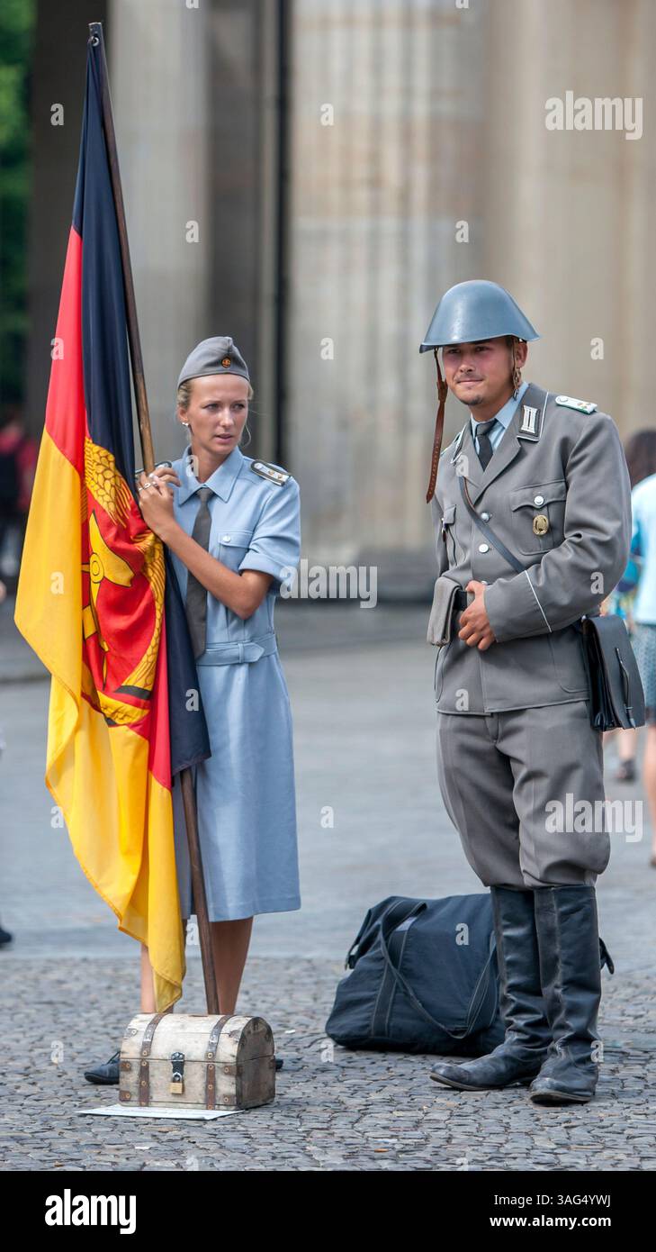 Als ehemalige deutsche Soldaten gekleidet, die die erste Flagge der DDR in der Nähe des Brandenburger Tors in Berlin halten. Stockfoto