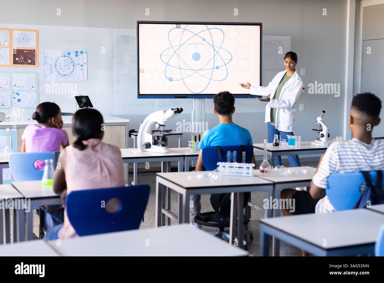 In der Schule präsentierte indische Lehrerin wissenschaftliche Diagramme auf dem Bildschirm den Schülern im Klassenzimmer Stockfoto