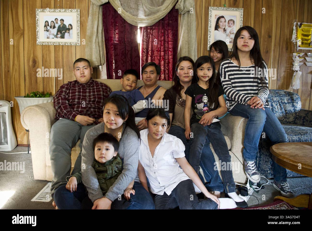 26. April 2012: Anchorage, AK, USA – Steve Vue lebt mit seiner zehnköpfigen Familie in Anchorage, Alaska. Seine Eltern, Koua Vue und Ia Yang, wurden in Hmong Flüchtlingslagern in Thailand geboren, verbrachten aber den größten Teil ihres Lebens in den USA und zogen 2008 von Kalifornien nach Alaska, in der Hoffnung, ihren Kindern ein besseres Leben zu bieten. Auf dem Boden sitzen von links Eric, Karen und Debbie. Auf dem Sofa sind Steve, Andy, Koua, Ia, Sunshine, Schatz und Sarah. (Kreditbild: © Marc Lester/MCT/ZUMAPRESS.com) Stockfoto