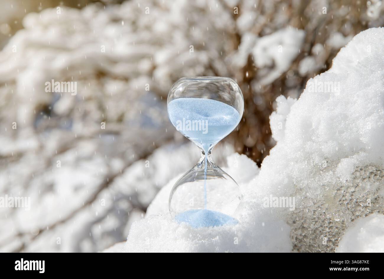 Konzeptionelles Bild des Umschaltens auf Winterzeit oder Rückfall, Ende der Sommerzeit. Selektiver Fokus auf Sanduhr mit blauem Sand. Stockfoto