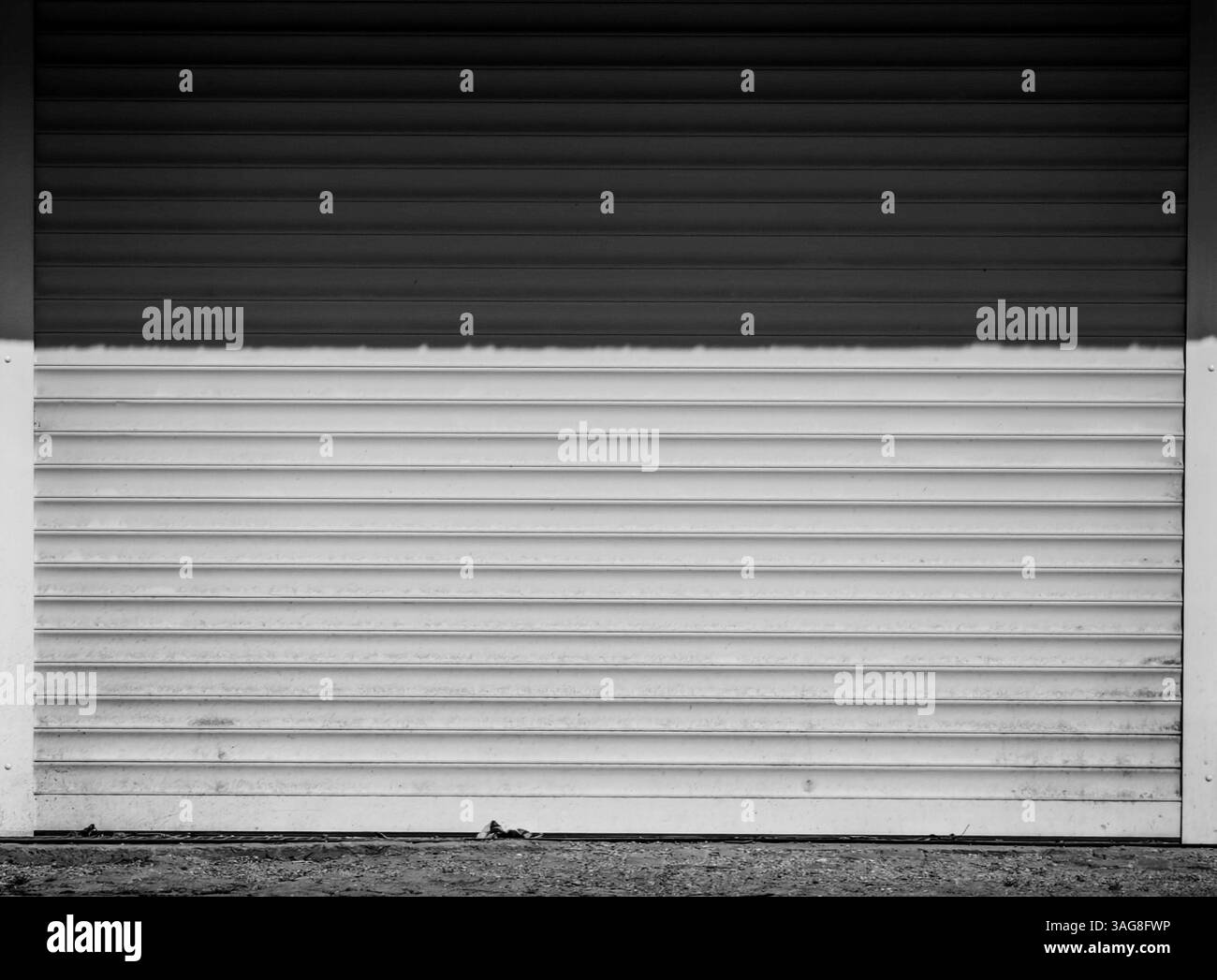 Geteiltes Licht: Schatten und Sonne auf weißem Garagentor Stockfoto