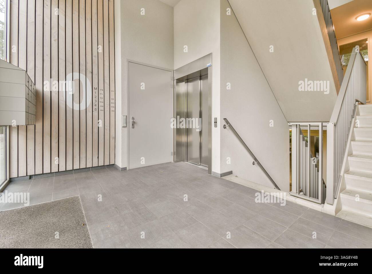 Ein elegantes und modernes Interieur mit einer Treppe neben einem Aufzug. Das Design besticht durch eine minimalistische Ästhetik mit klaren Linien und neutralen Farben. Stockfoto