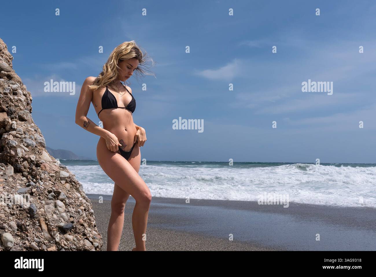 Das wunderschöne venezolanische, blonde Bikinimodell genießt die Schönheit des Alboran Sea und genießt im Urlaub ein herrliches Strandglück. Stockfoto