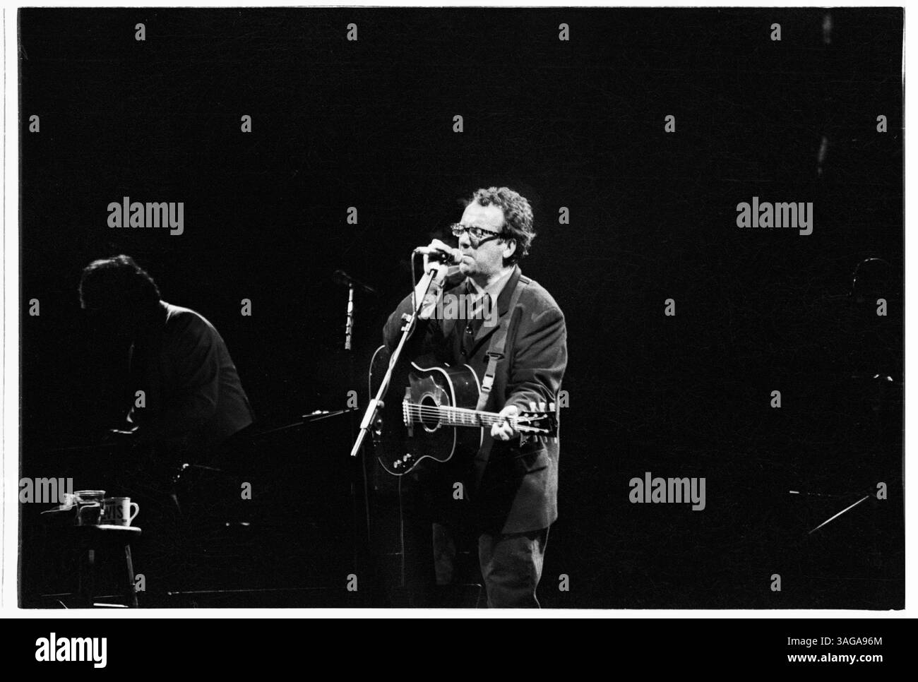 ELVIS COSTELLO, GLASTONBURY FESTIVAL, 1994: Elvis Costello und die Attraktionen spielen live auf der Pyramid Stage beim Glastonbury Festival, England, 25. Juni 1994. Das Datum wurde als das letzte Festivaldatum in Großbritannien angekündigt. Foto: Rob Watkins. INFO: Elvis Costello ist ein englischer Singer-Songwriter und Musiker, der für seinen scharfen Witz und seine genreübergreifende Musik gefeiert wird. Mit der Punk- und New Wave-Bewegung in den späten 1970er Jahren haben Hits wie „Alison“ und „My AIM Is True“ seinen legendären Status gestärkt. Stockfoto ELVIS COSTELLO, GLASTONBURY FESTIVAL, 1994: Elvis Costello und die Attraktionen spielen live auf der Pyramid Stage beim Glastonbury Festival, England, 25. Juni 1994. Das Datum wurde als das letzte Festivaldatum in Großbritannien angekündigt. Foto: Rob Watkins. INFO: Elvis Costello ist ein englischer Singer-Songwriter und Musiker, der für seinen scharfen Witz und seine genreübergreifende Musik gefeiert wird. Mit der Punk- und New Wave-Bewegung in den späten 1970er Jahren haben Hits wie „Alison“ und „My AIM Is True“ seinen legendären Status gestärkt. Stockfoto