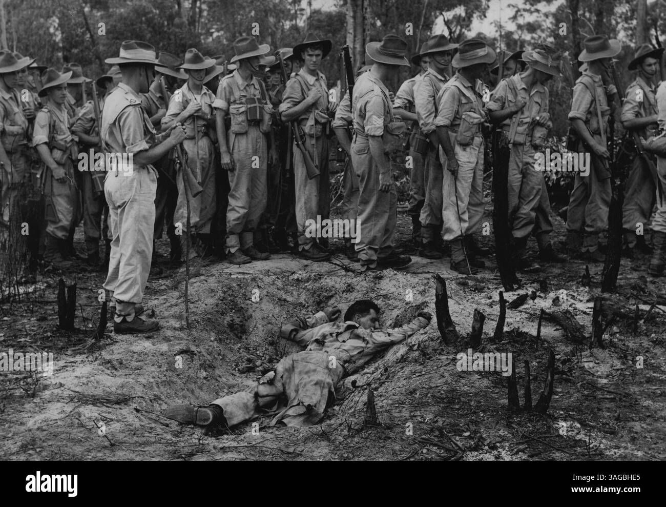Atombombenausbildung -- Mitglieder des 13 National Service Training Battalion wurden heute in der Verteidigung gegen Atomkrieg in Greenhills bei Liverpool angewiesen. Eine "Bombe" aus Gelignit, Benzin und Diesel wurde explodiert, und die Wirkung von Explosion, Hitze und Strahlung wurde von zuvor vorbereiteten "Verletzten" simuliert, die in verschiedenen Arten von Gräben, von einem "Muschelschaber" bis hin zu richtig gegrabenen Waffengästen mit überdachten Schlafplätzen und Schutz vor Atomexplosionen, geschützt waren. Hier untersuchen die Mitglieder die Wirkung auf Sgt R Hitchins ARA attd auf den 13. NST. BN, da er in seinen flachen liegt Stockfoto
